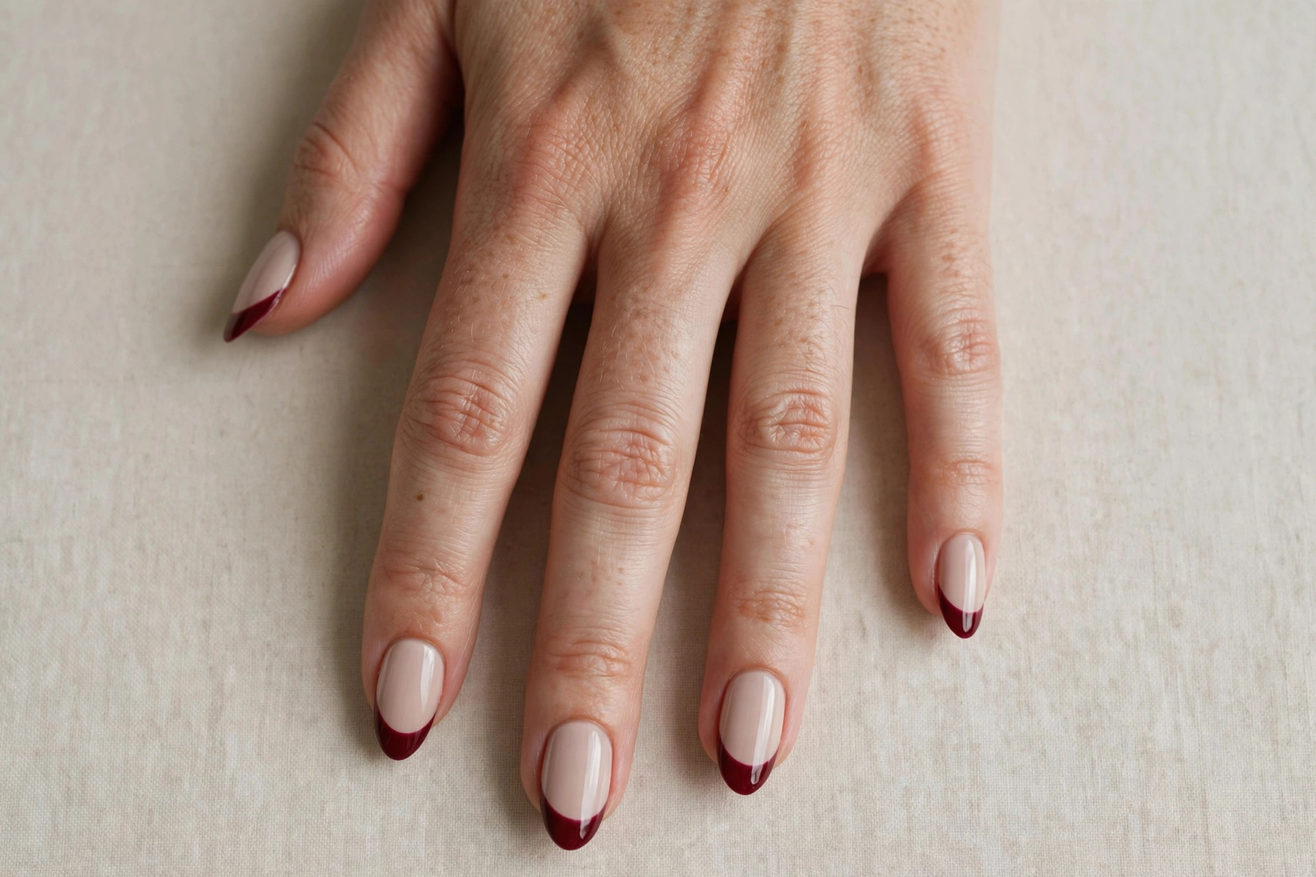 Deep burgundy French tips on a pale neutral base, a fall nail design
