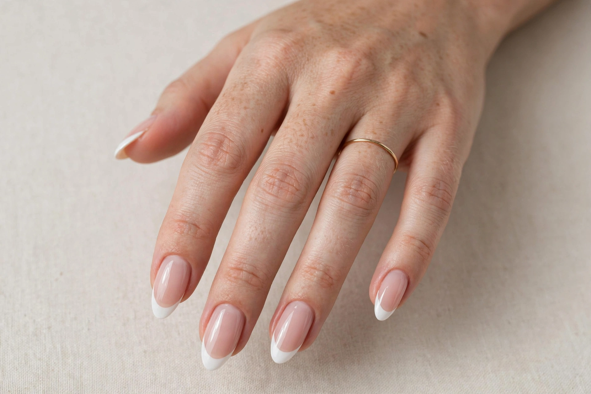 Close-up of a woman's hand with white French tip almond-shaped acrylic nails