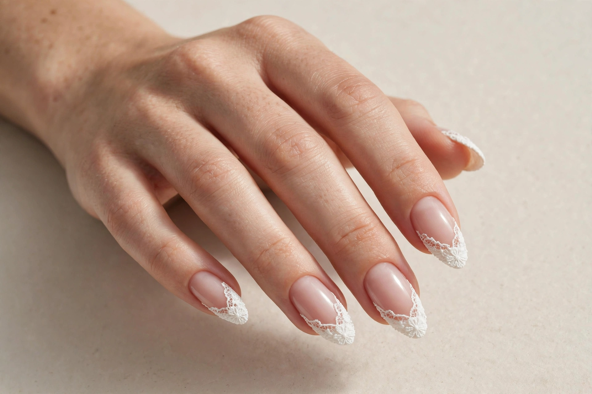 White lace patterned French tip manicure on almond nails