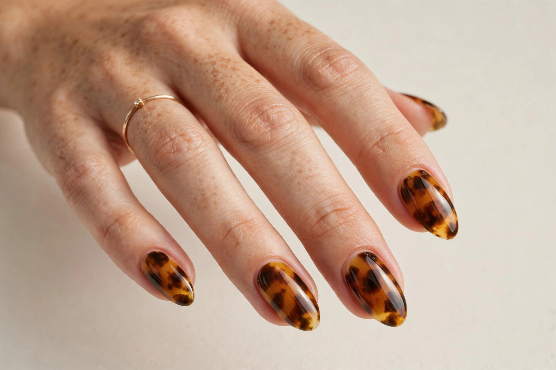 Close-up of a woman's hand with amber tortoiseshell pattern fall manicure