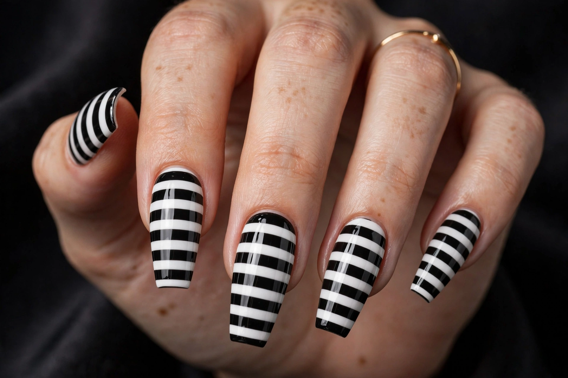 Long coffin nails painted in bold horizontal black and white stripes like the iconic suit, glossy finish