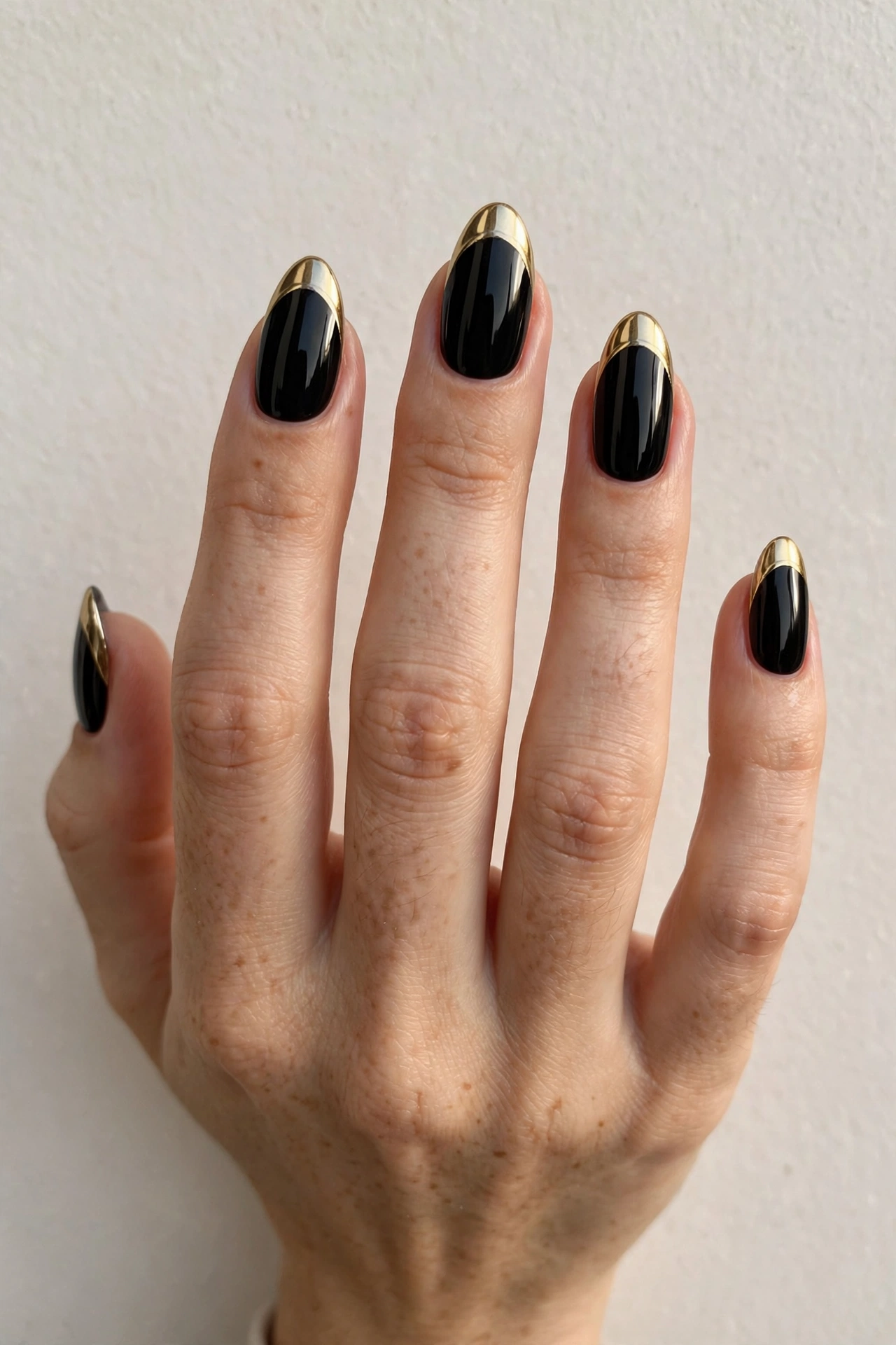 Black nails with gold chrome French tips on almond-shaped nails