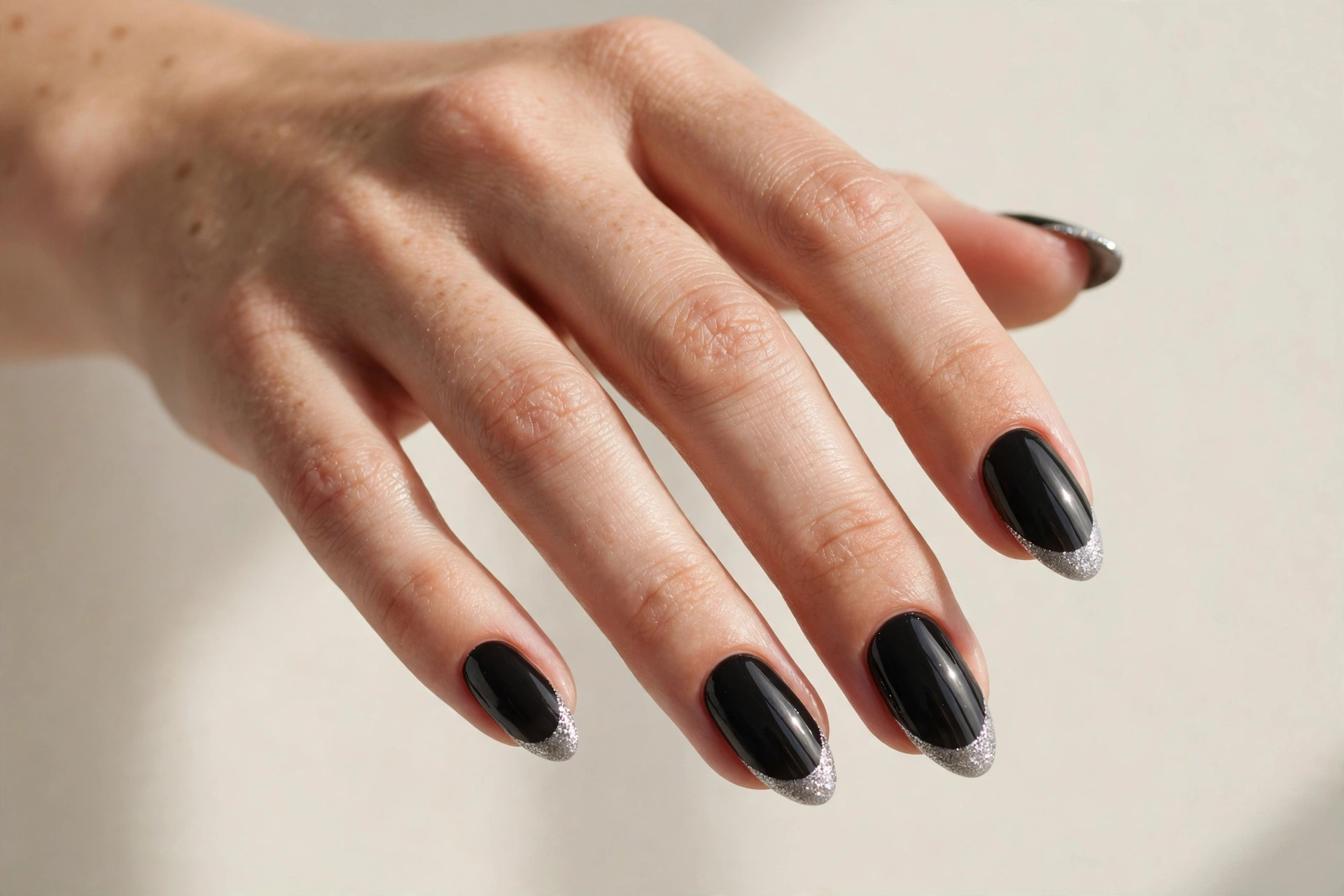 Silver glitter French tip nails on a black base