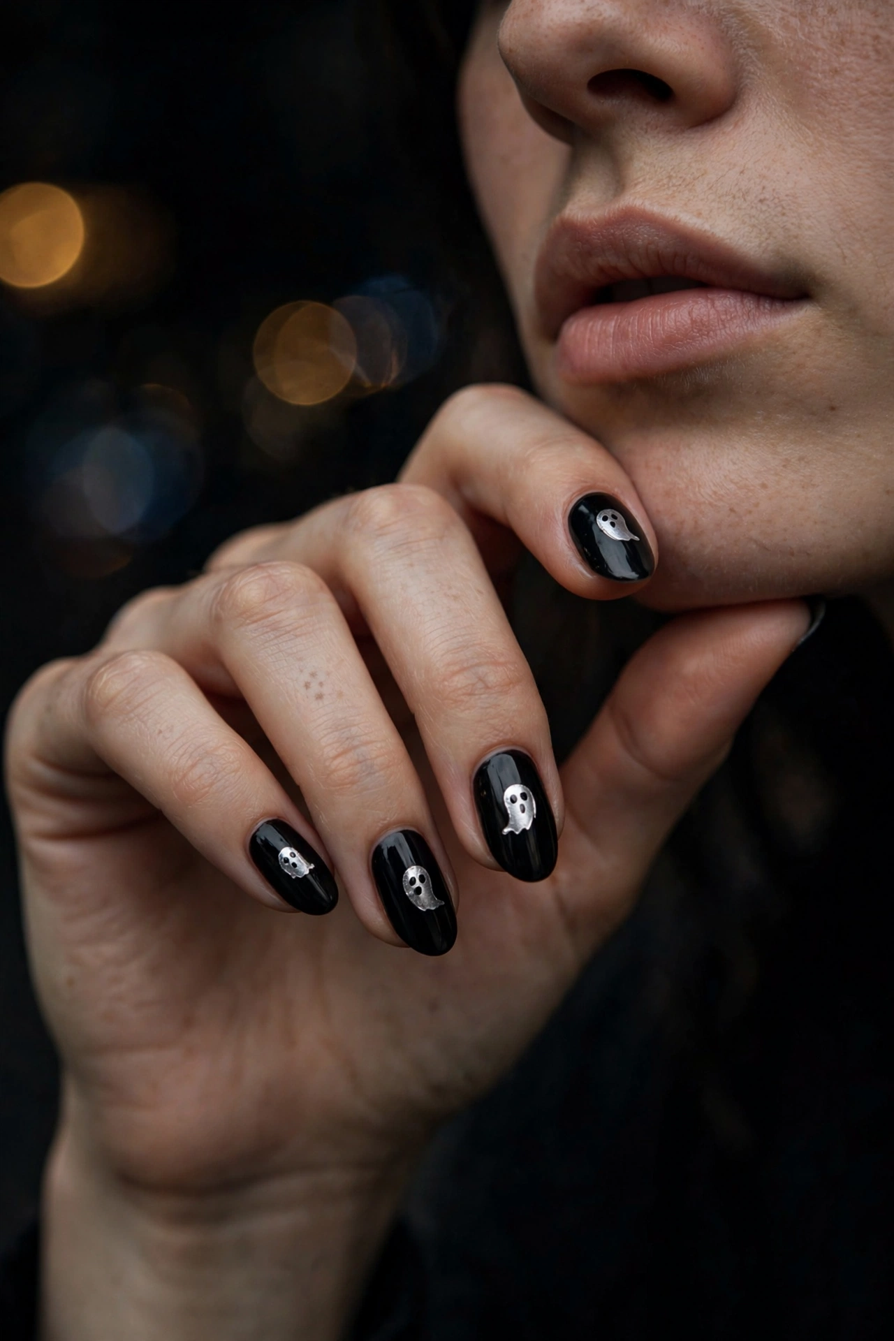 Black nails with silver ghost face Halloween nail art