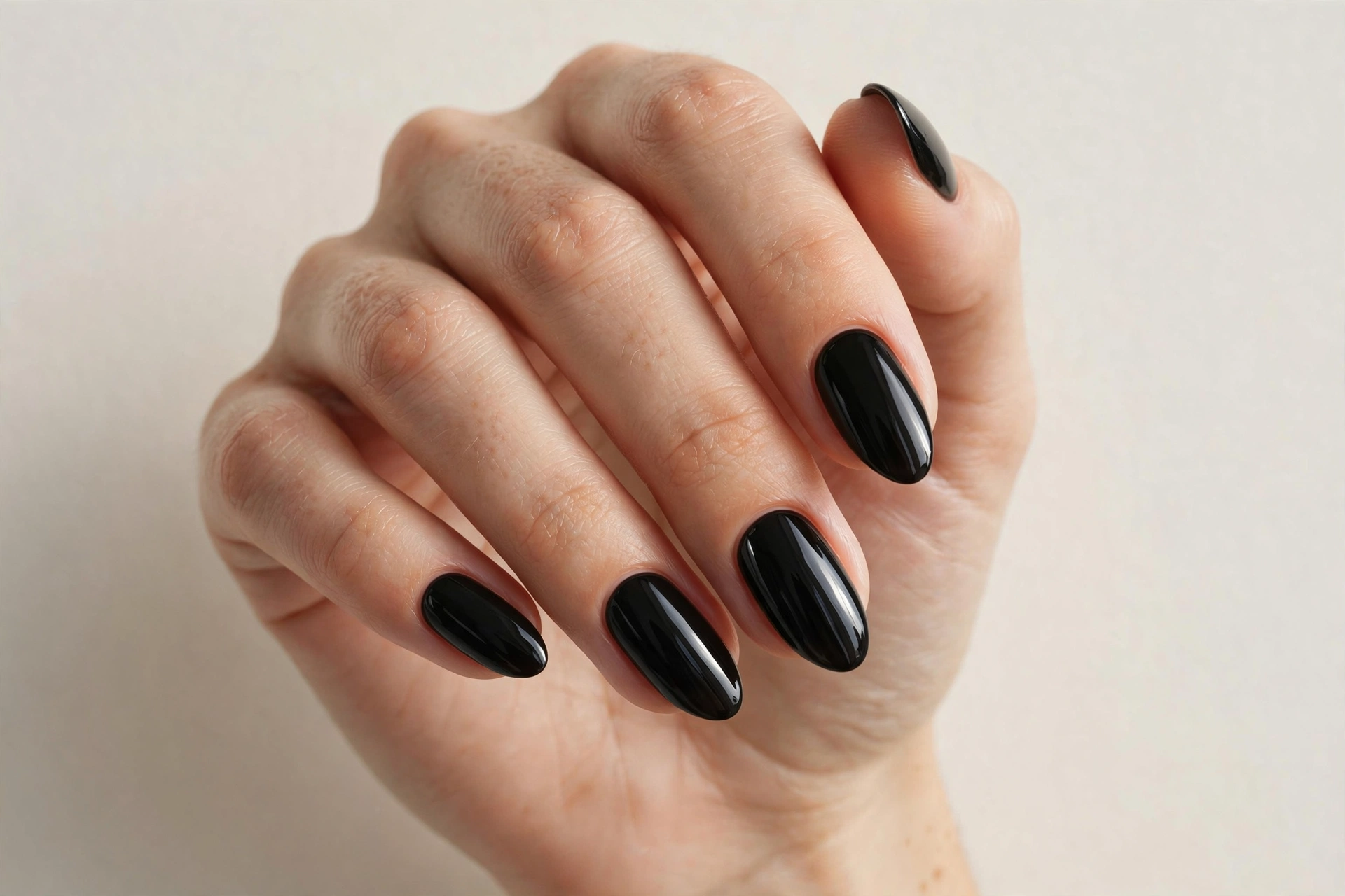 Glossy jet-black nail polish on almond shaped nails