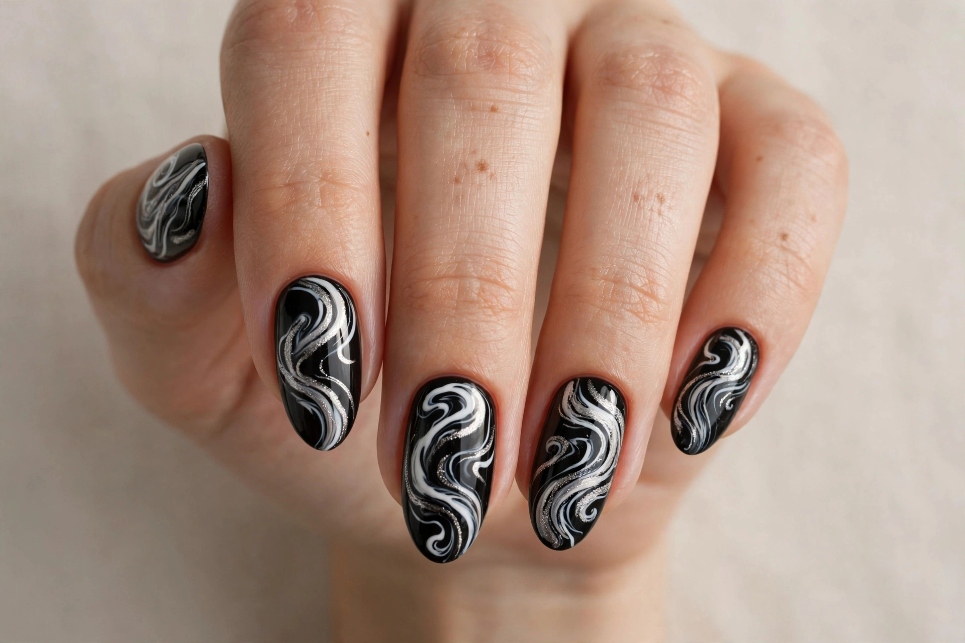 Black nail art with abstract white and silver swirls