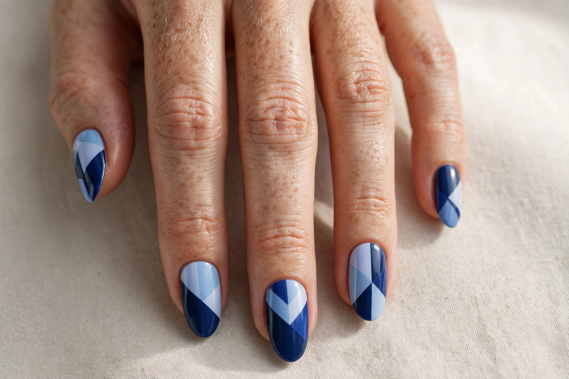 Two-tone blue geometric manicure with navy and pastel blue angular blocks on almond nails