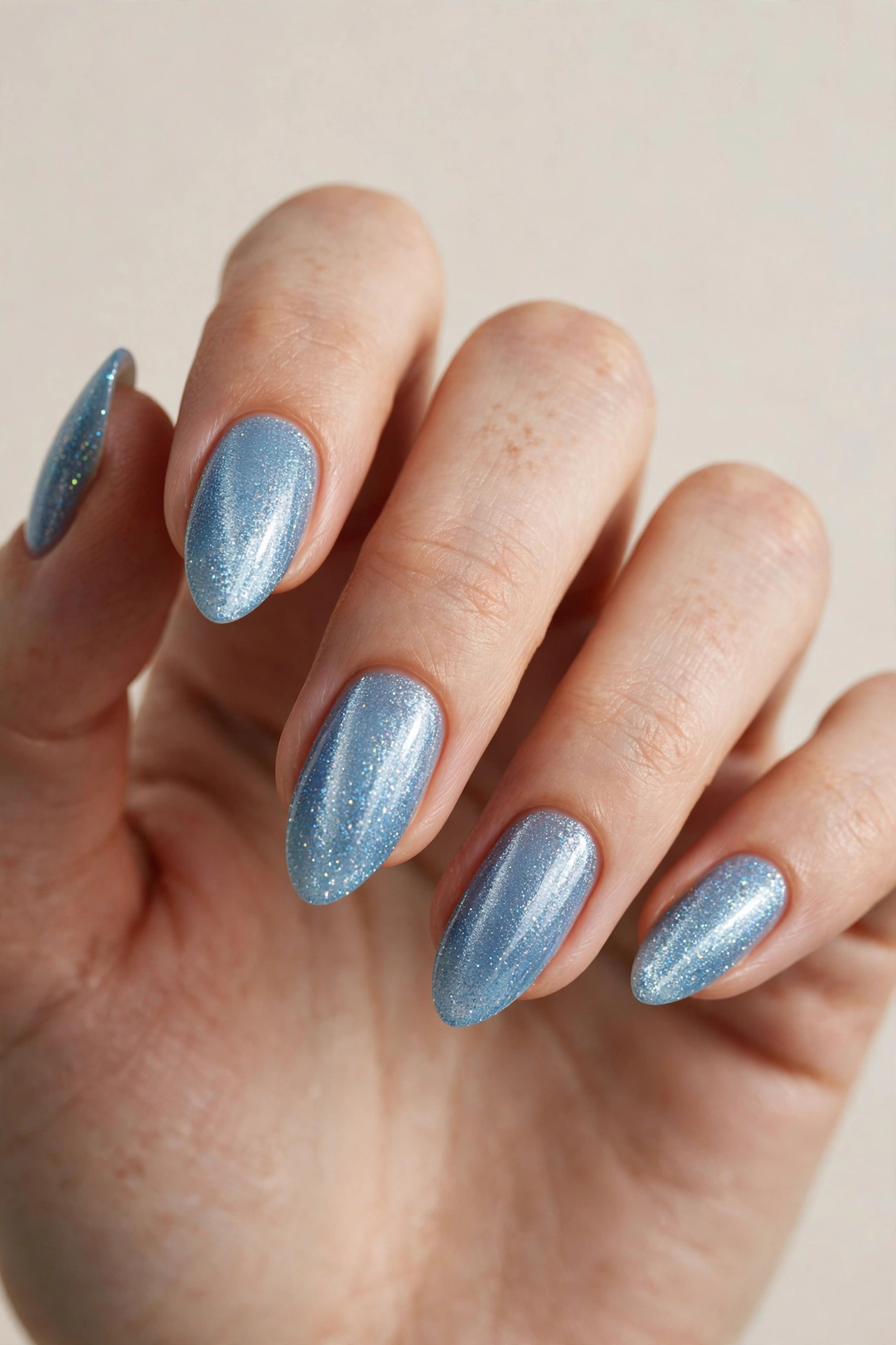 Close-up of a hand with shimmery ice blue glitter manicure