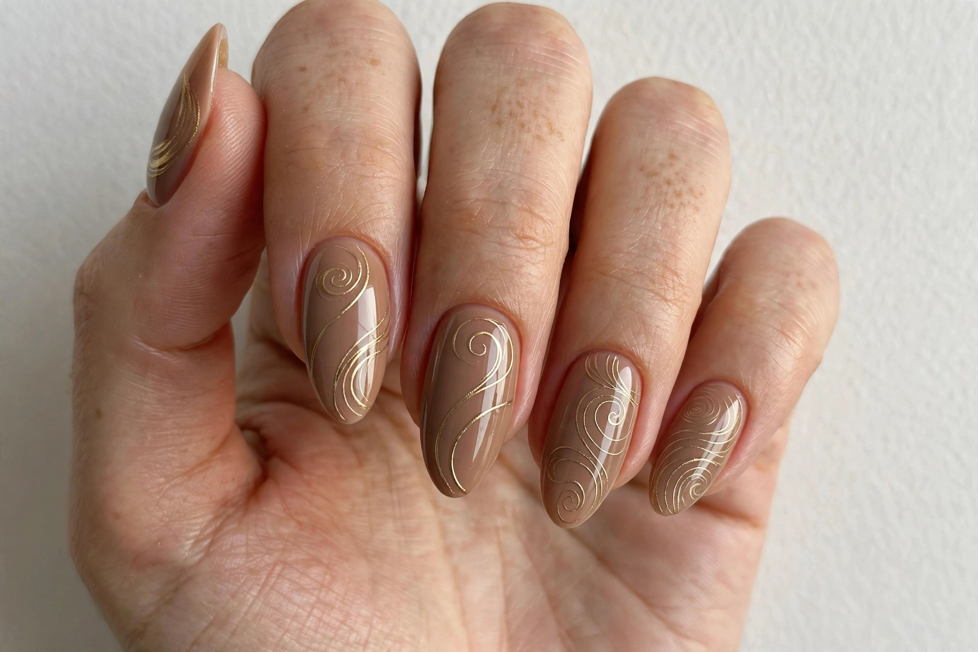 Creamy latte brown nails with gold swirl line art