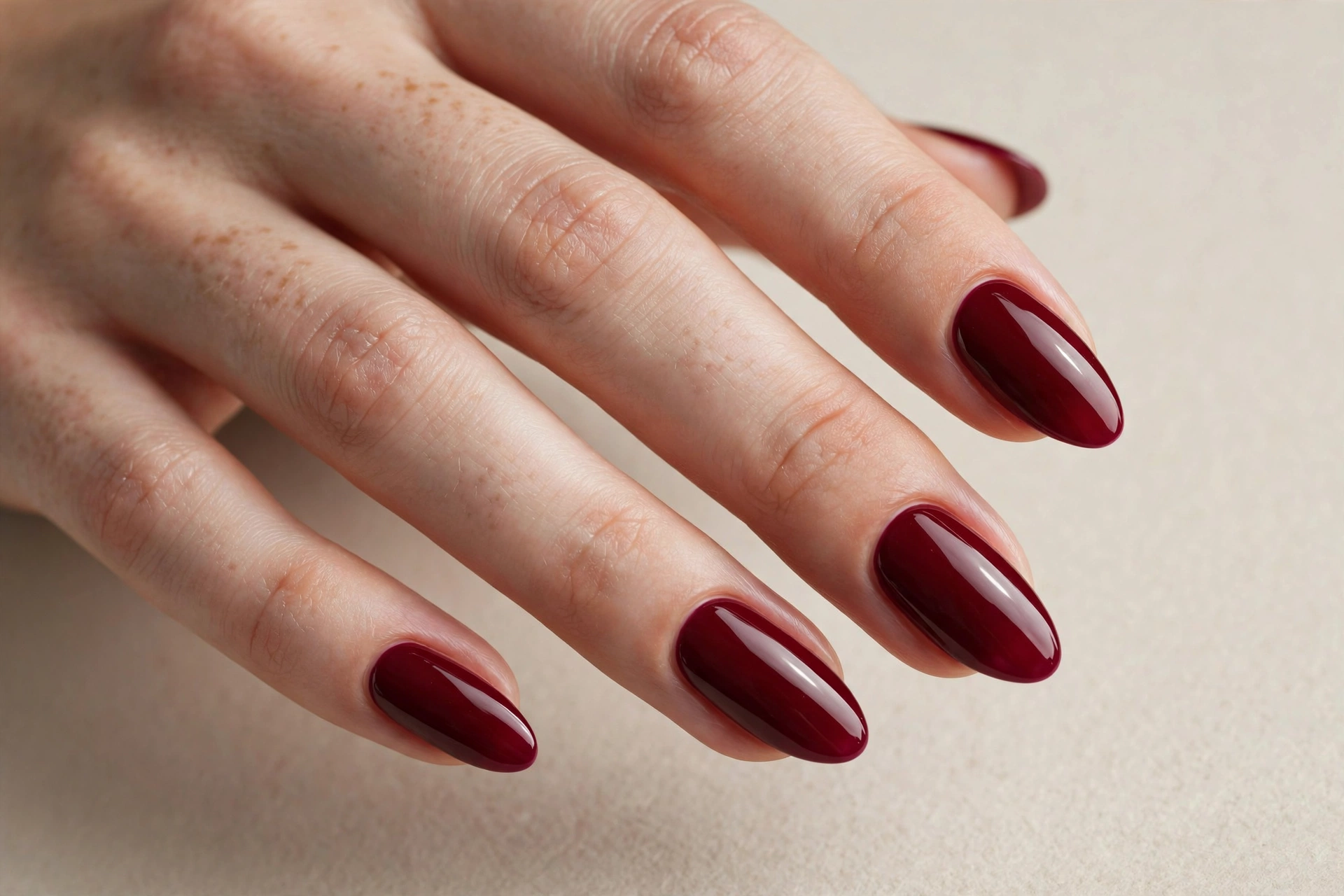 Glossy solid burgundy wine-red manicure on almond shaped nails