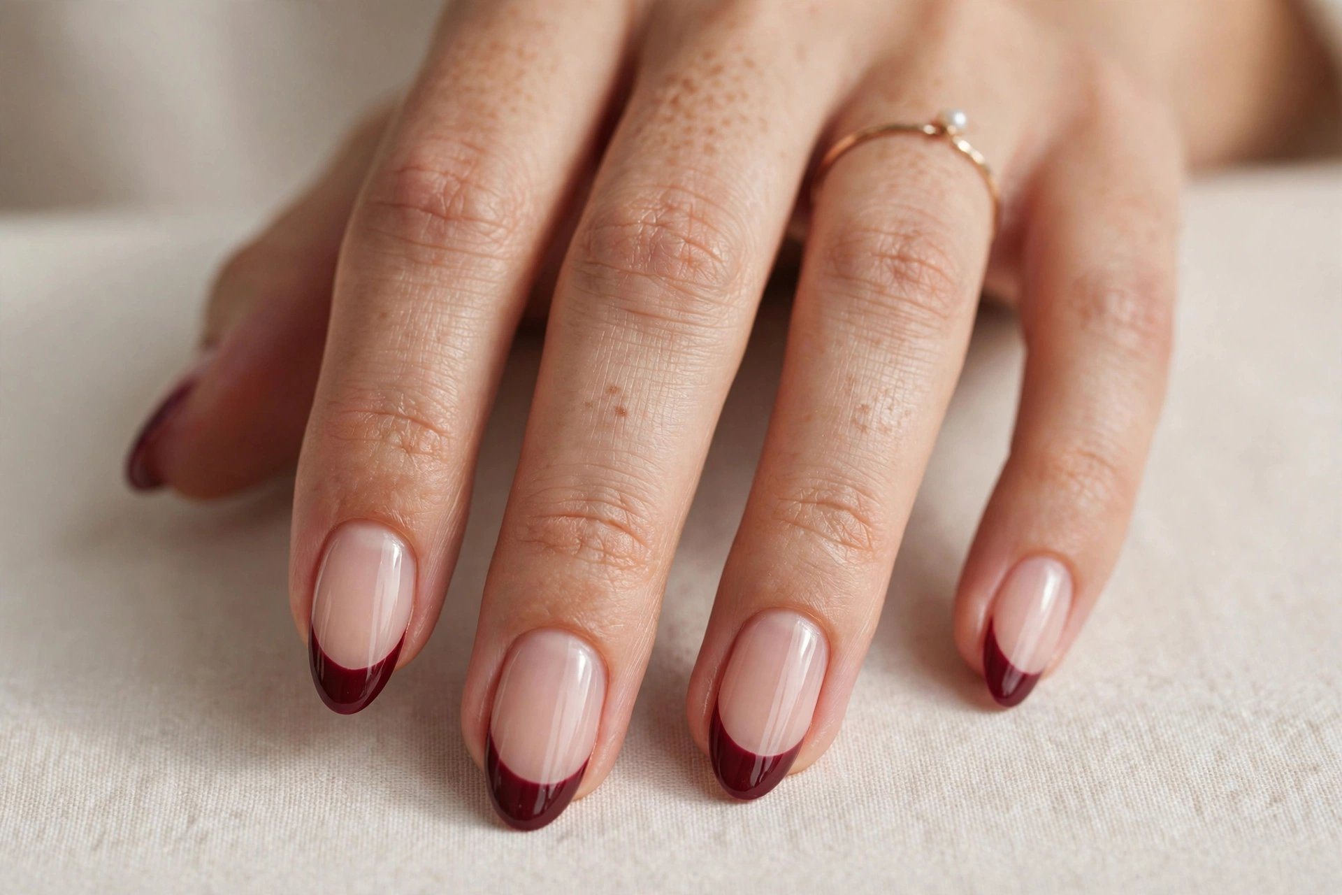 Burgundy almond nails with gold foil leaf on the tips