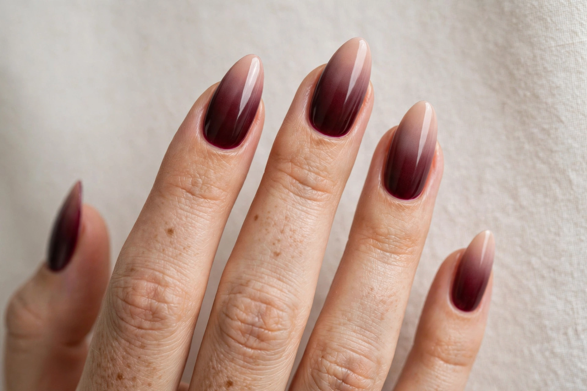 Bold burgundy ombre nails with deep wine tips on long almond nails