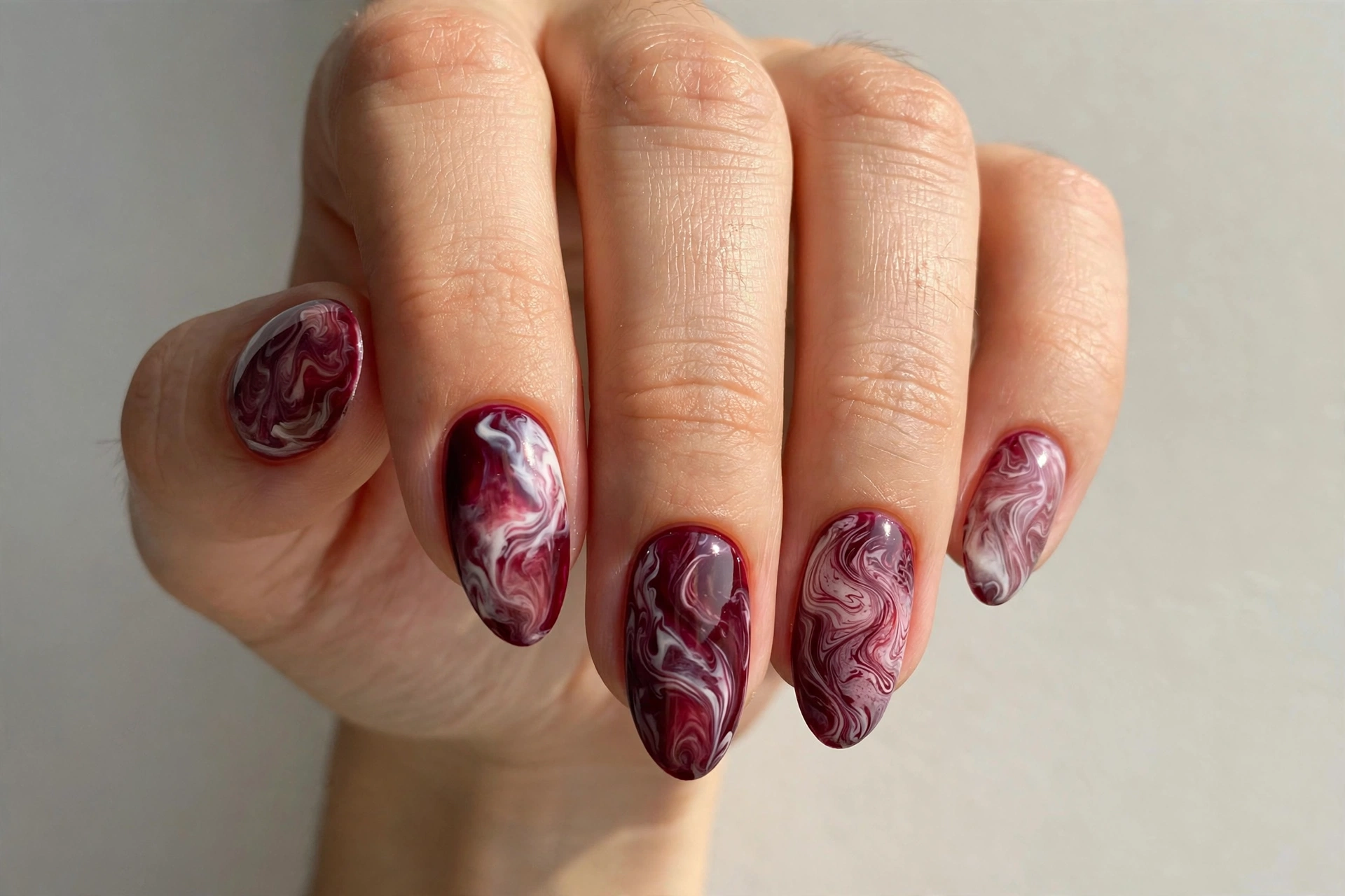 Burgundy and white marble swirl nail art on almond nails