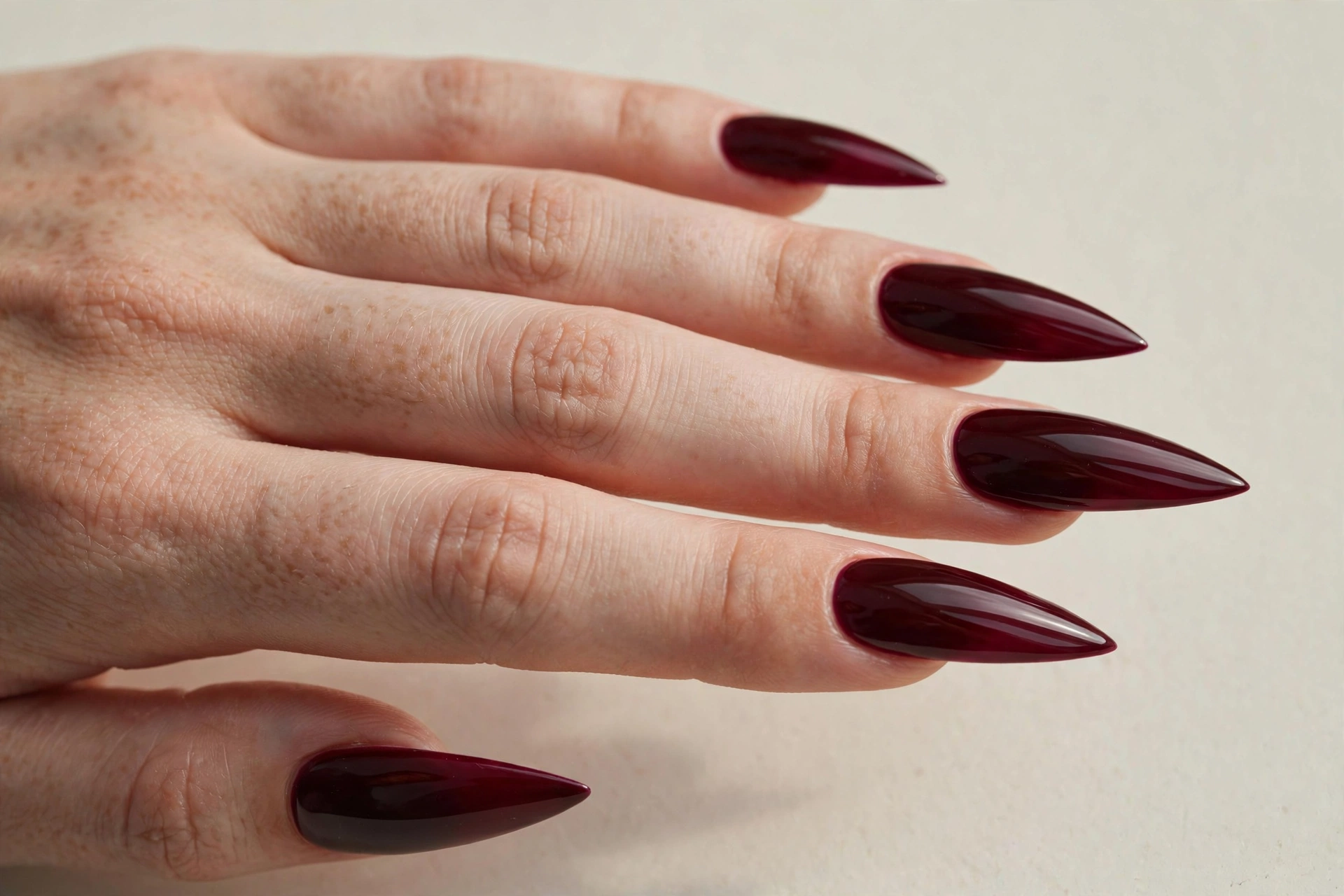 Glossy burgundy stiletto nails with sharp pointed tips