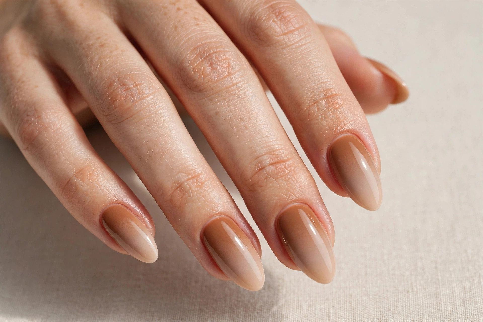 Close-up of a woman's hand with caramel to nude ombre fall manicure