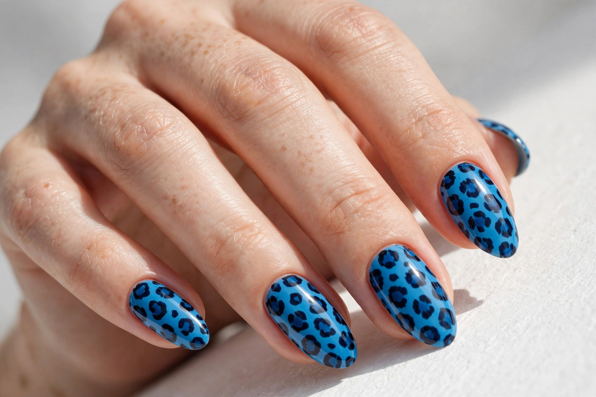 Blue cheetah print nail art with dark navy spots
