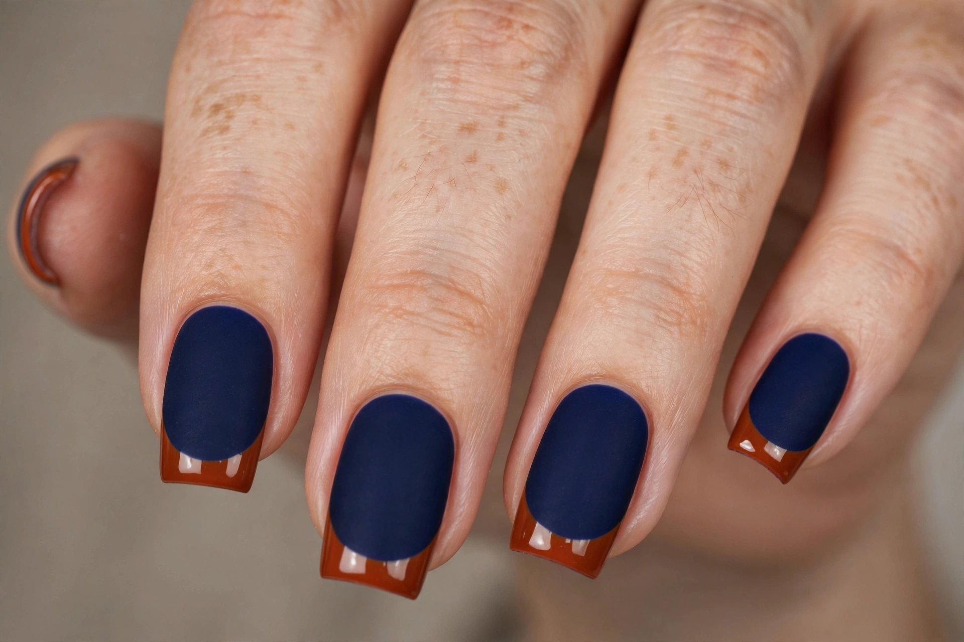 Square shaped nails with matte navy base and glossy orange tips