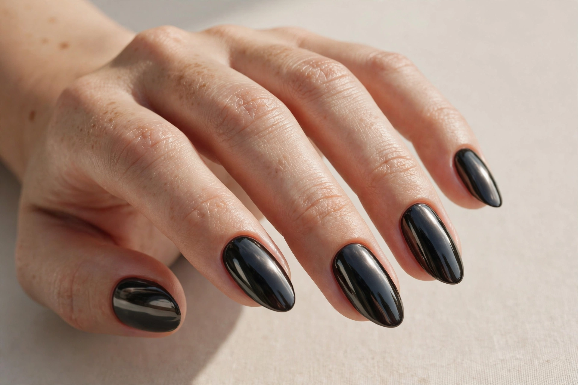 Dark black mirror chrome nails with a glossy reflective finish