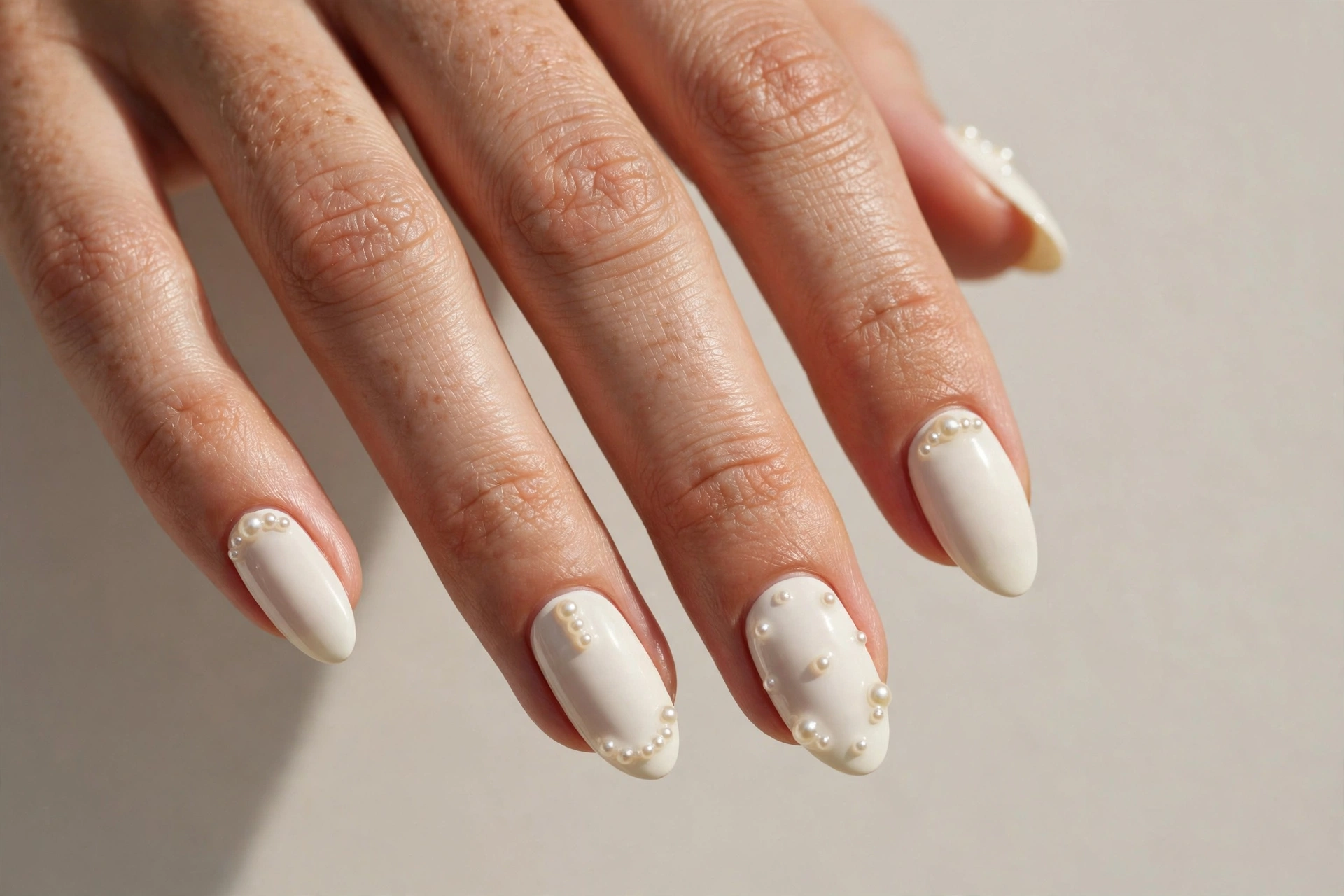 Ivory manicure with tiny pearl embellishments on the nails