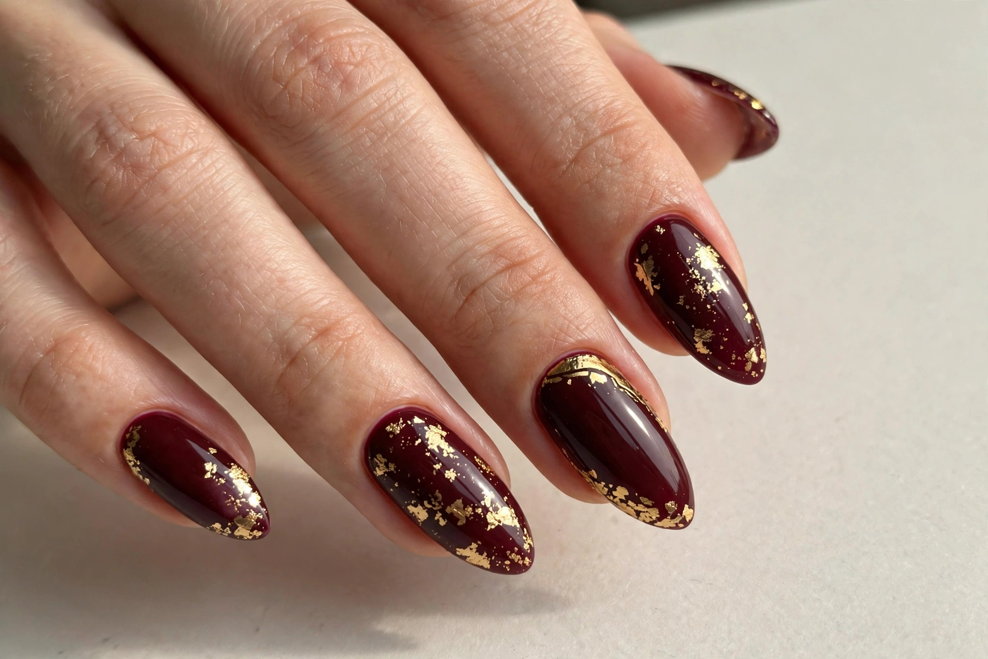 Deep burgundy manicure with gold foil accent details