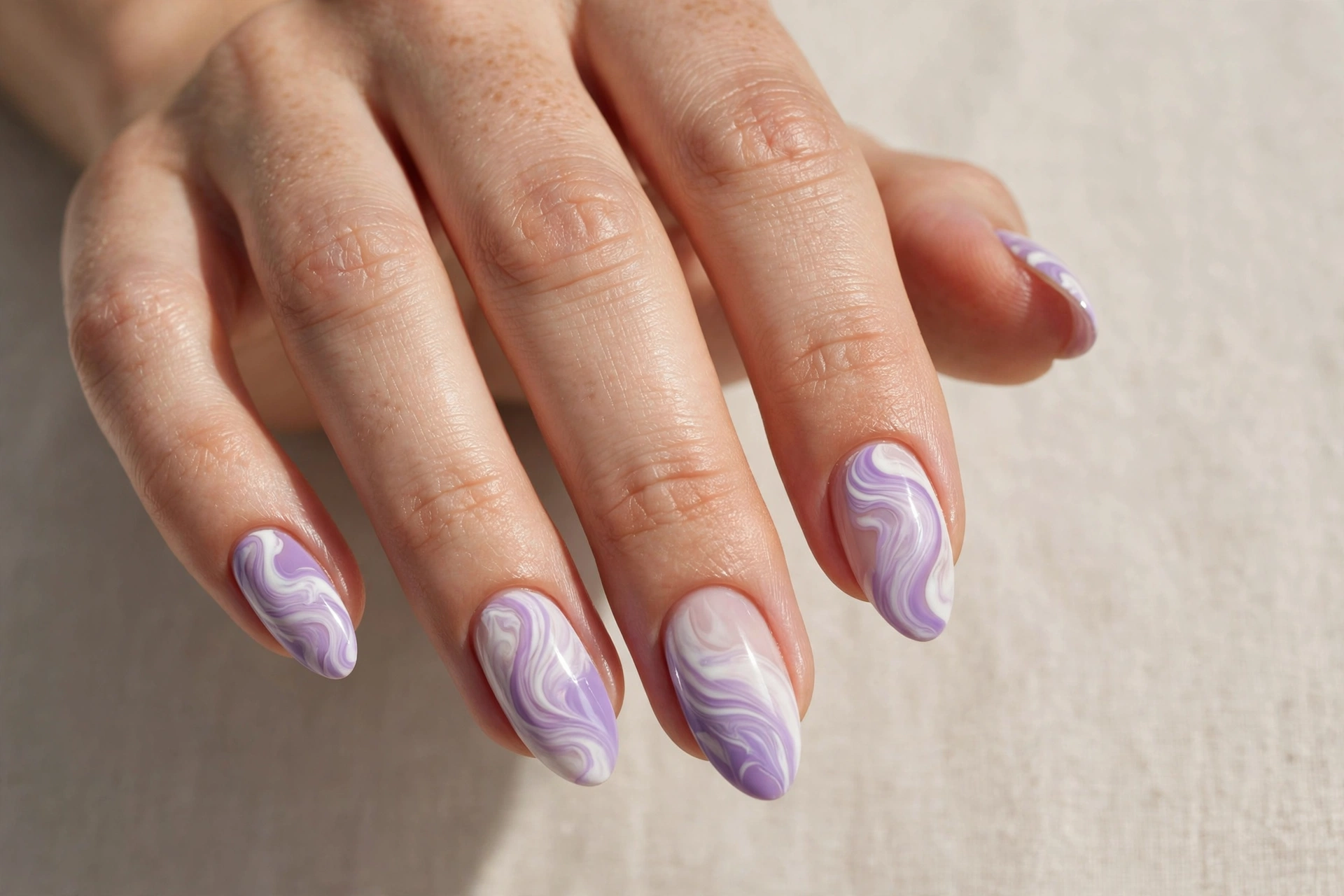 Close-up of lavender and white swirl nail art manicure on almond shaped nails