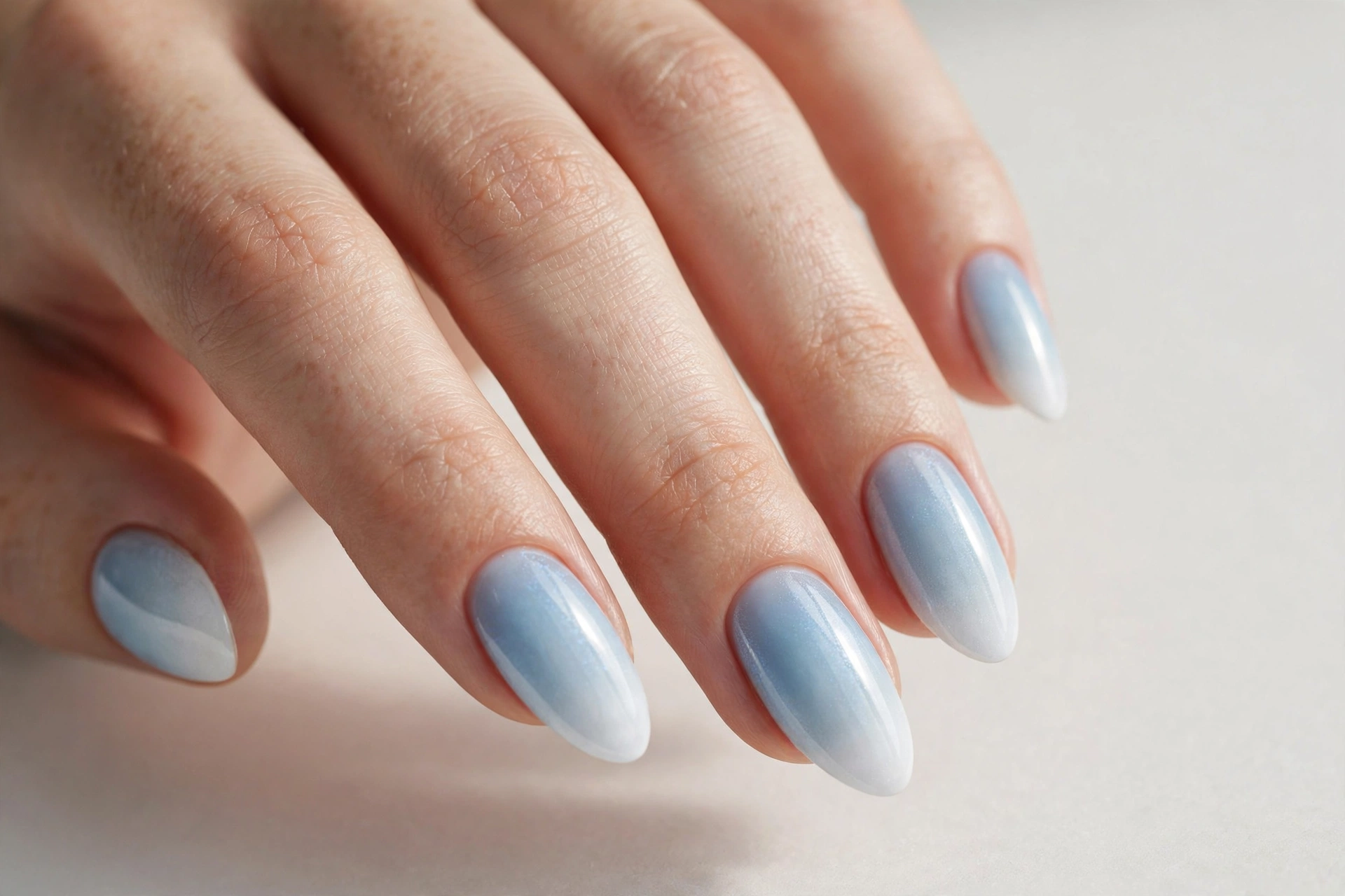 Icy blue ombré winter nails fading from pale blue to snowy white tips
