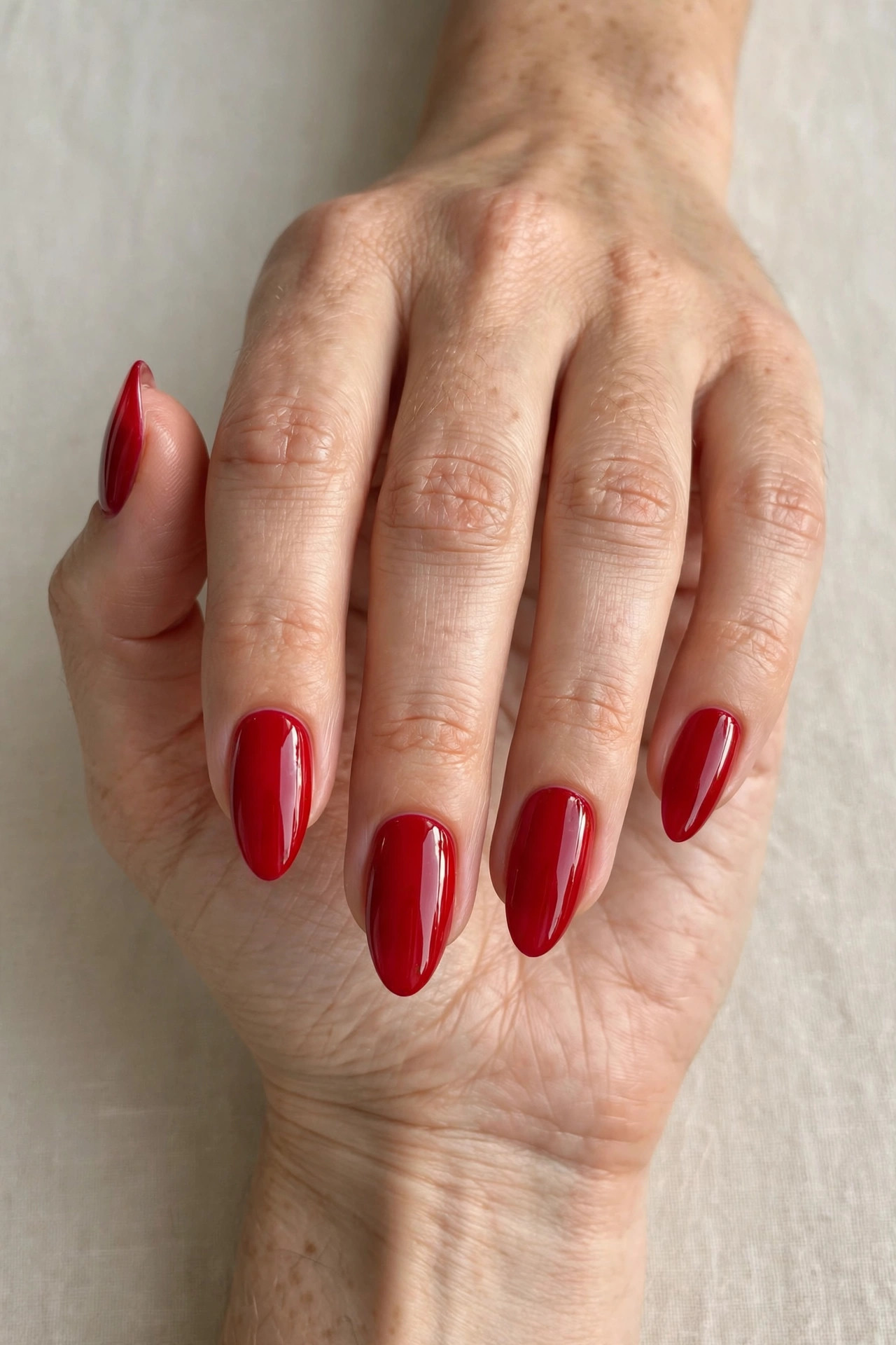 Close-up of a woman's hand with classic glossy red Christmas nails, almond shaped nails