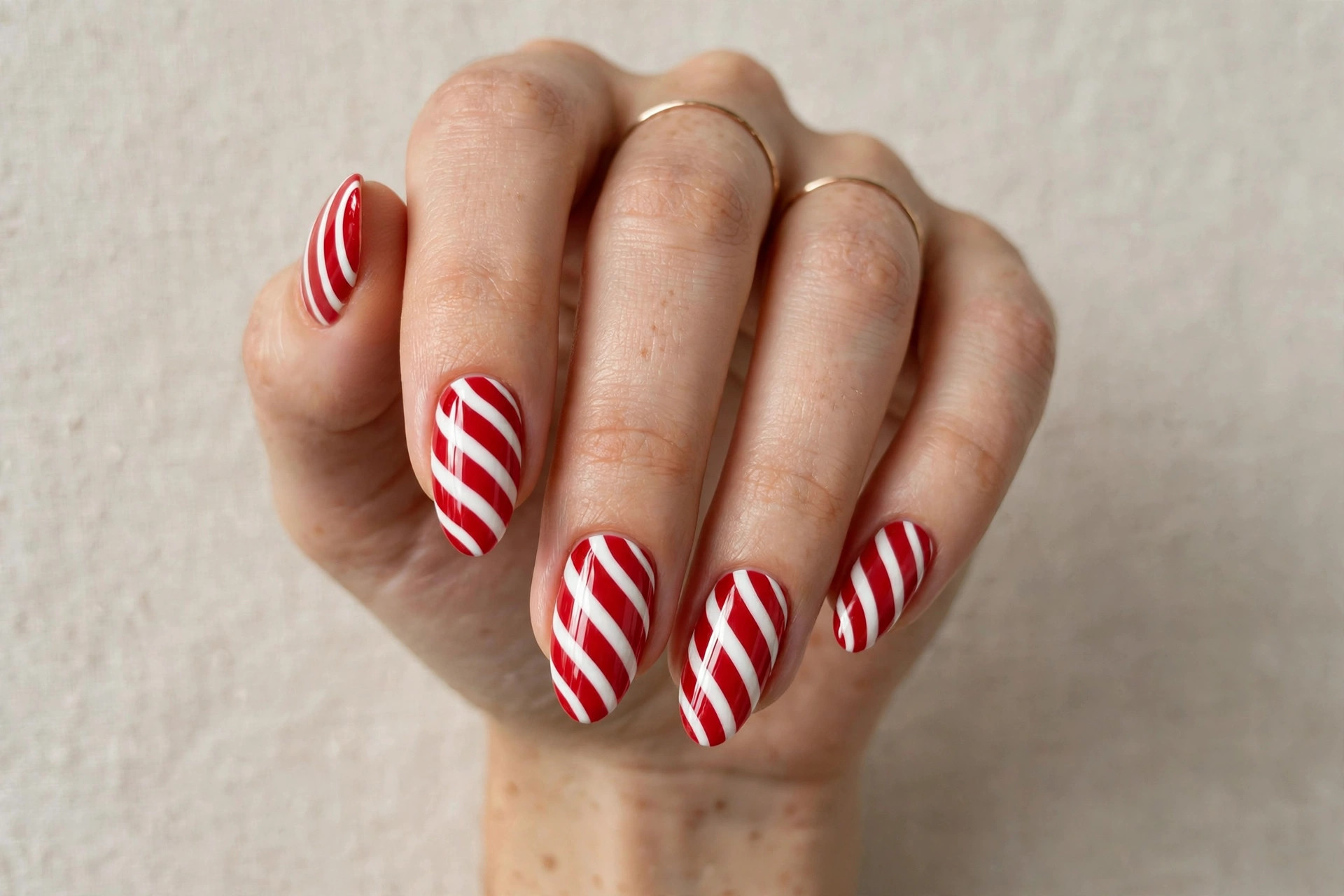 Close-up of a woman's hand with red and white candy cane striped Christmas nails