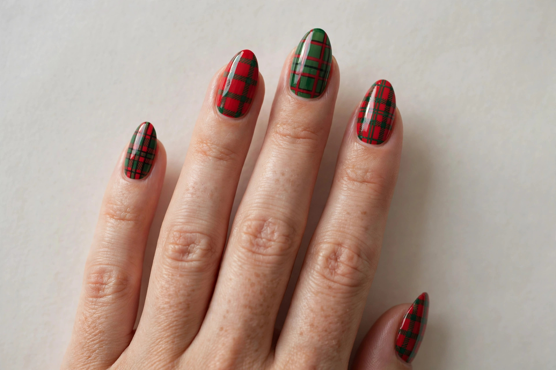 Close-up of a woman's hand with red and green Christmas plaid checkered nail art