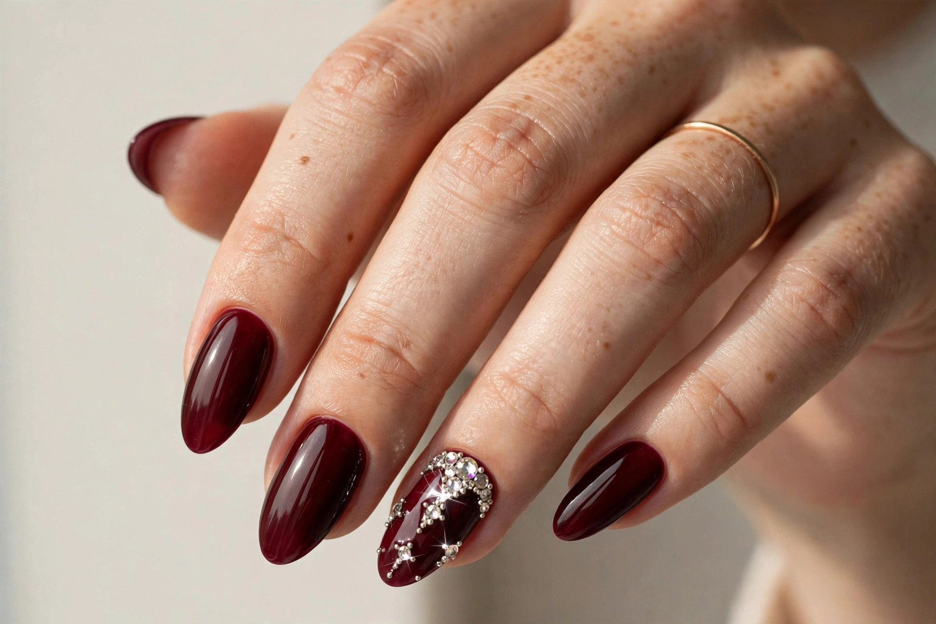 Dark wine red nails with rhinestone embellishments