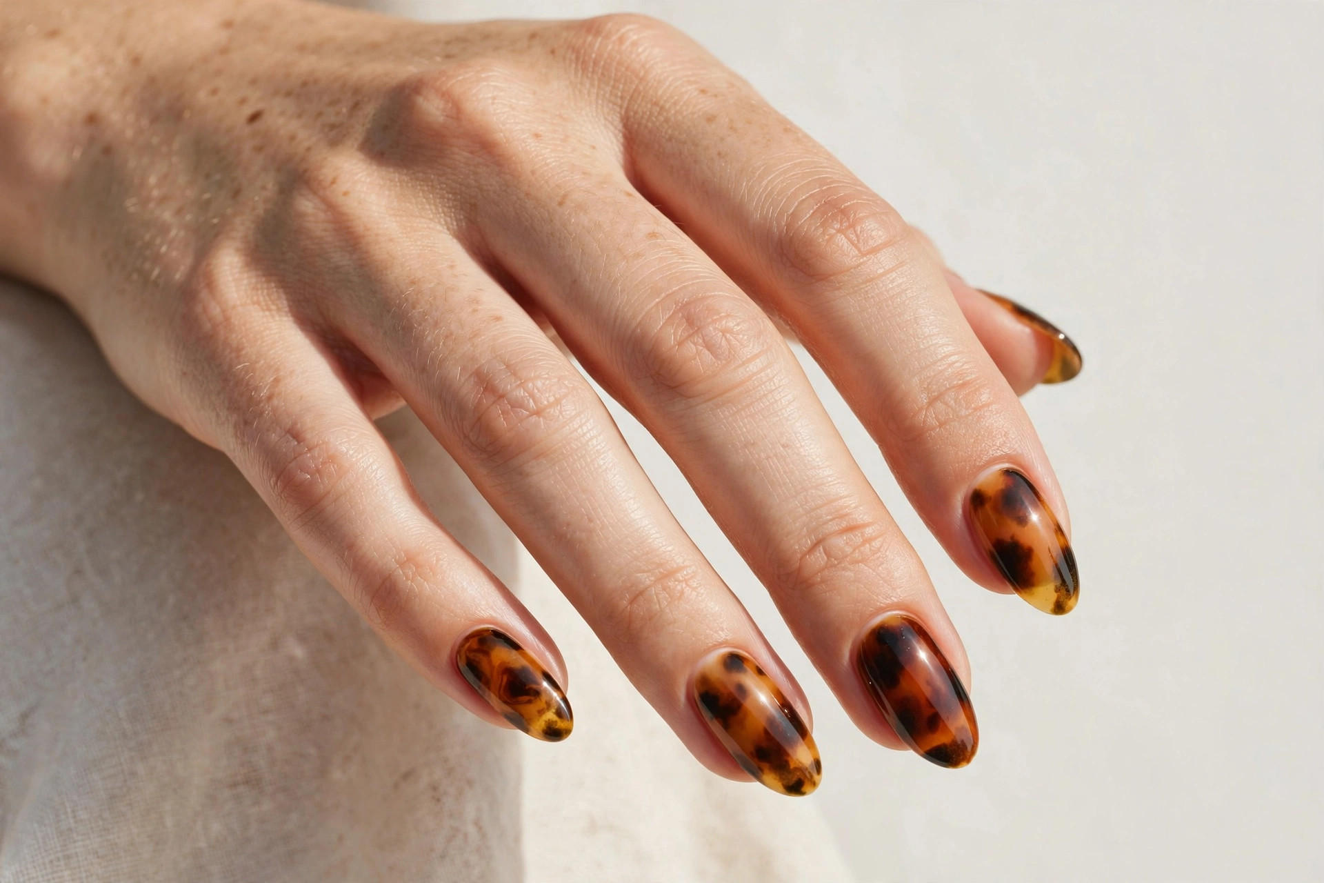 Tortoiseshell pattern nails in amber brown and caramel tones on almond nails