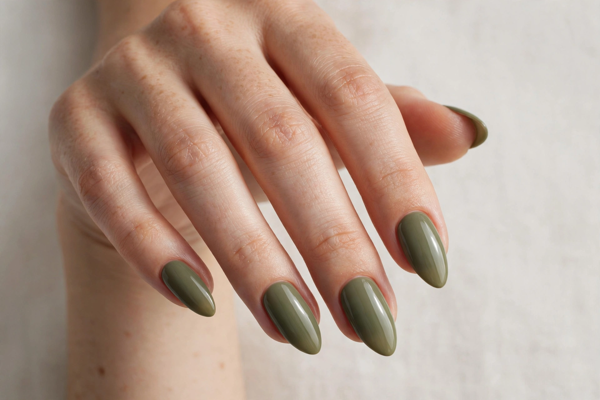 Almond-shaped nails in solid muted olive green polish