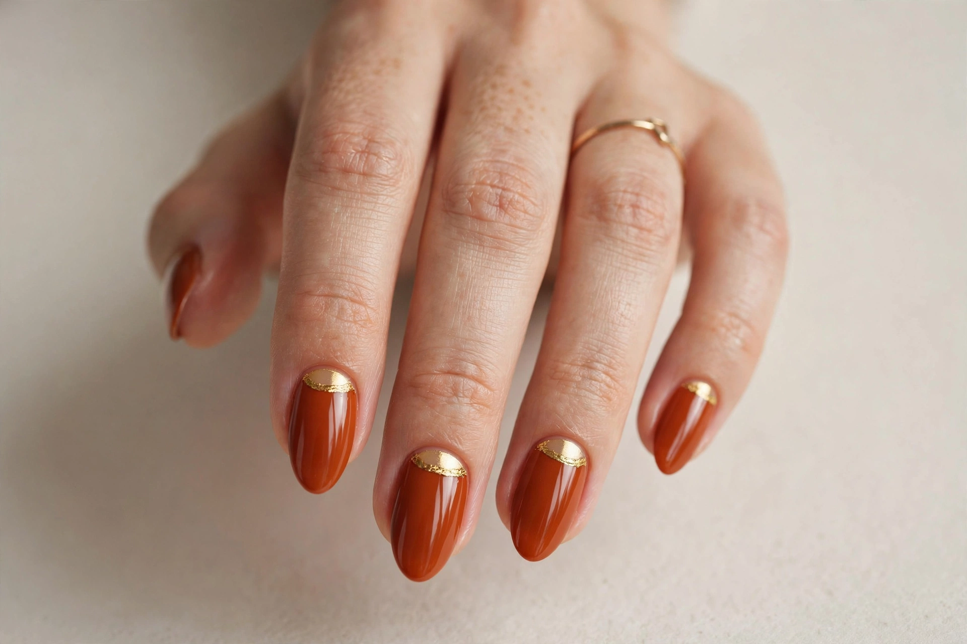 Burnt orange half-moon manicure with gold cuticle detail
