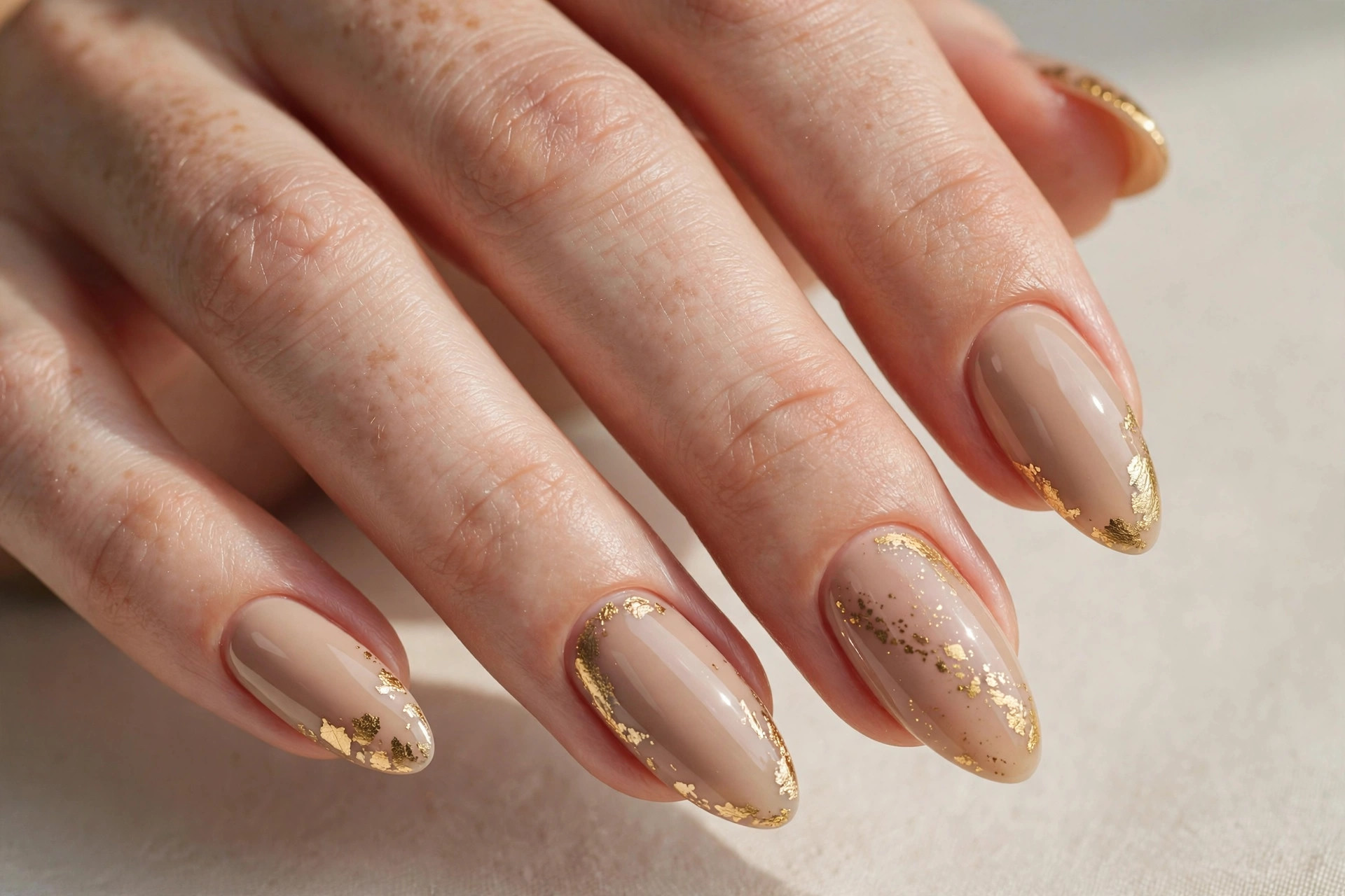 Nude beige nails with elegant gold foil accents