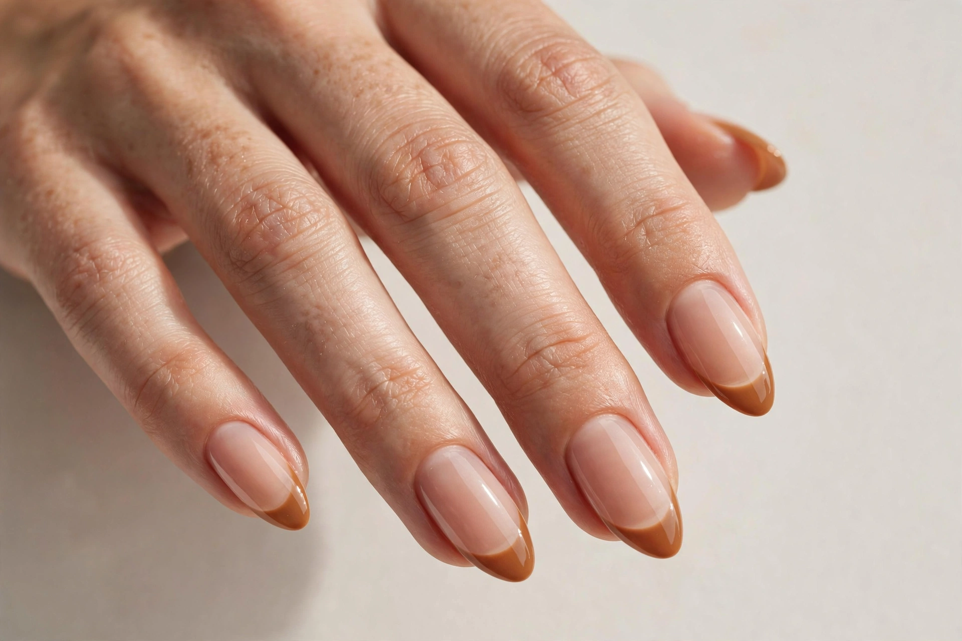 Caramel french tip manicure on sheer nude base