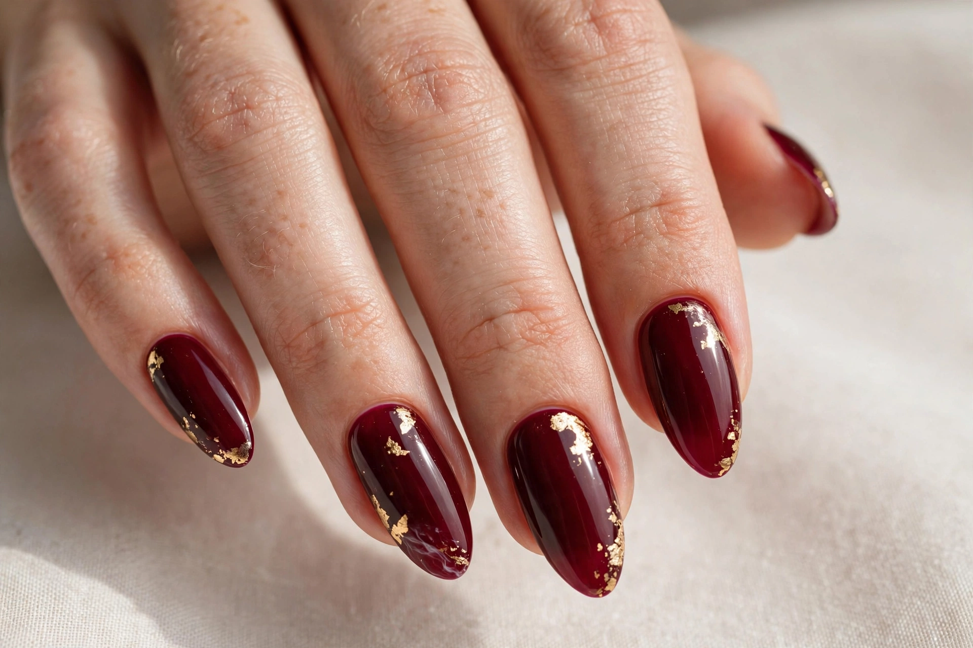Burgundy acrylic nails with delicate gold foil accents