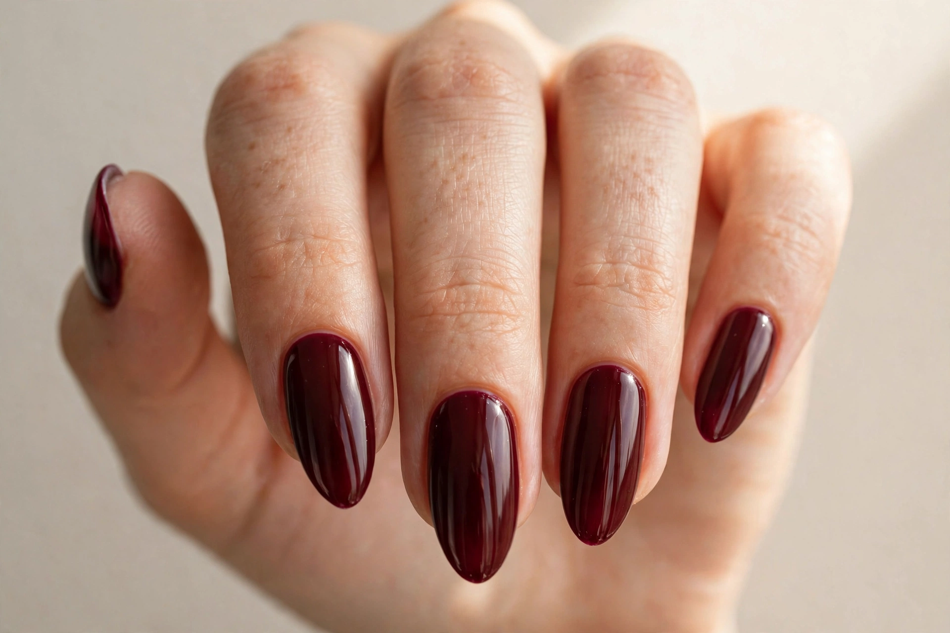 Deep burgundy glossy manicure on almond nails
