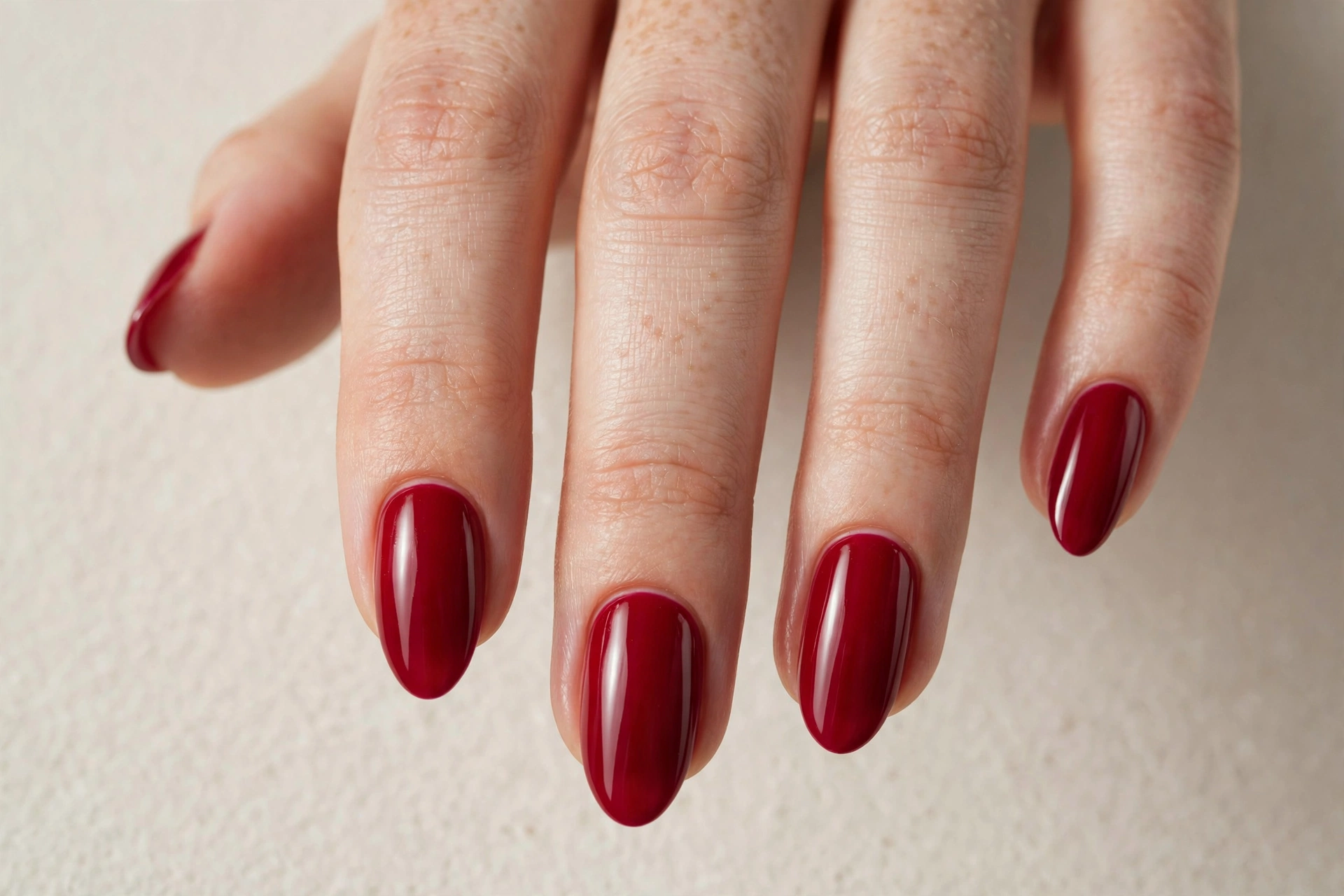 Cranberry red manicure on almond-shaped nails