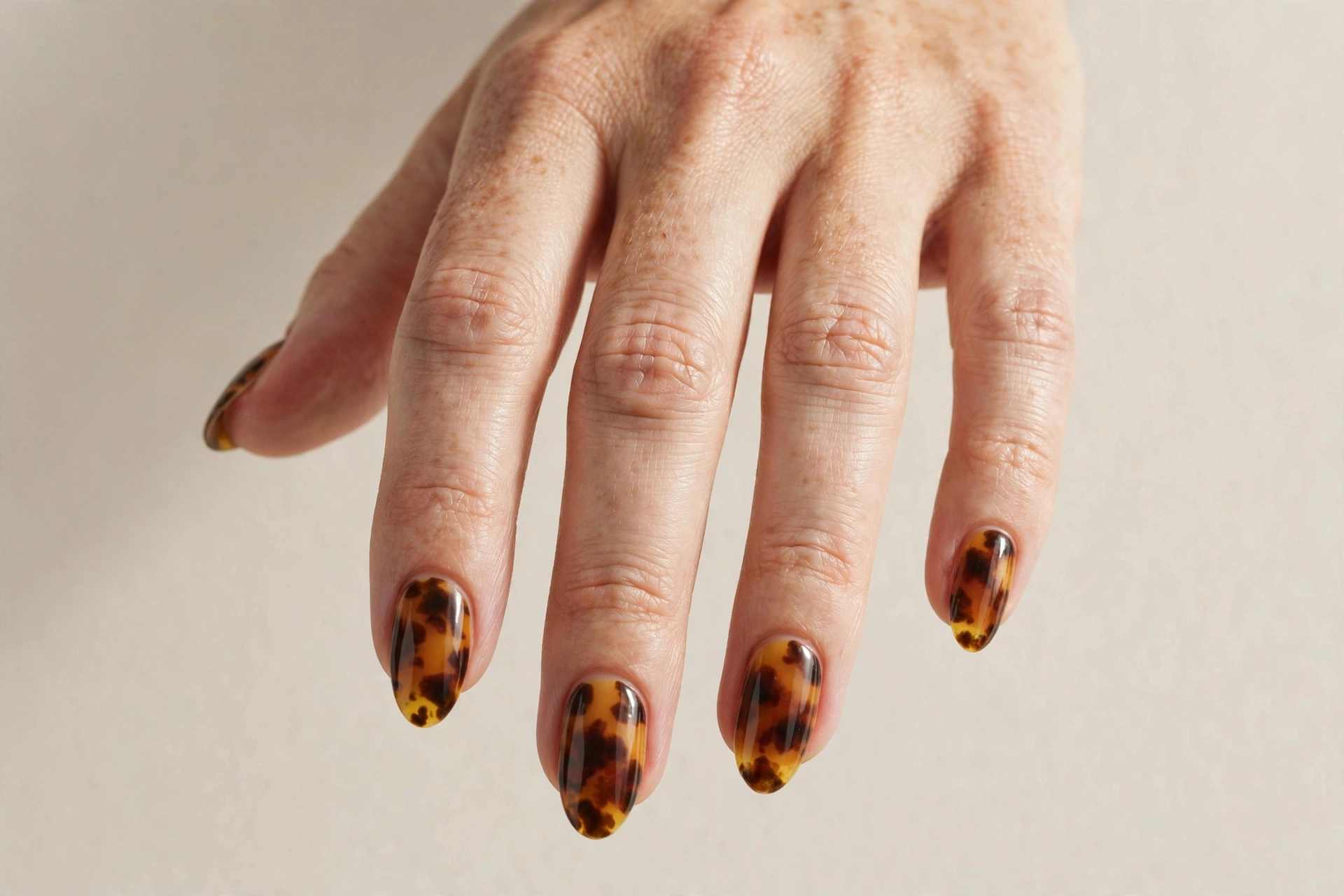 Close-up of a hand with tortoiseshell amber and brown patterned nails