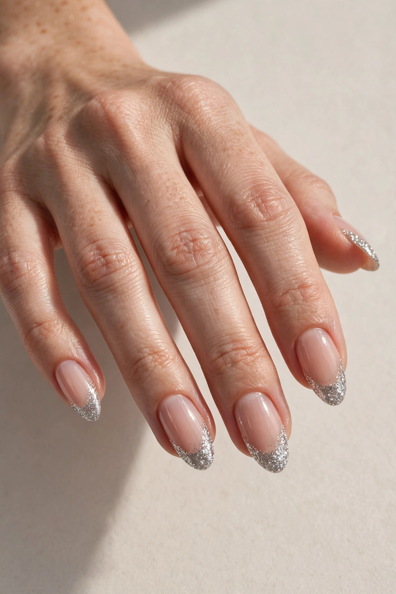 Glitter French tip manicure with sparkling silver glitter tips on sheer nude nails