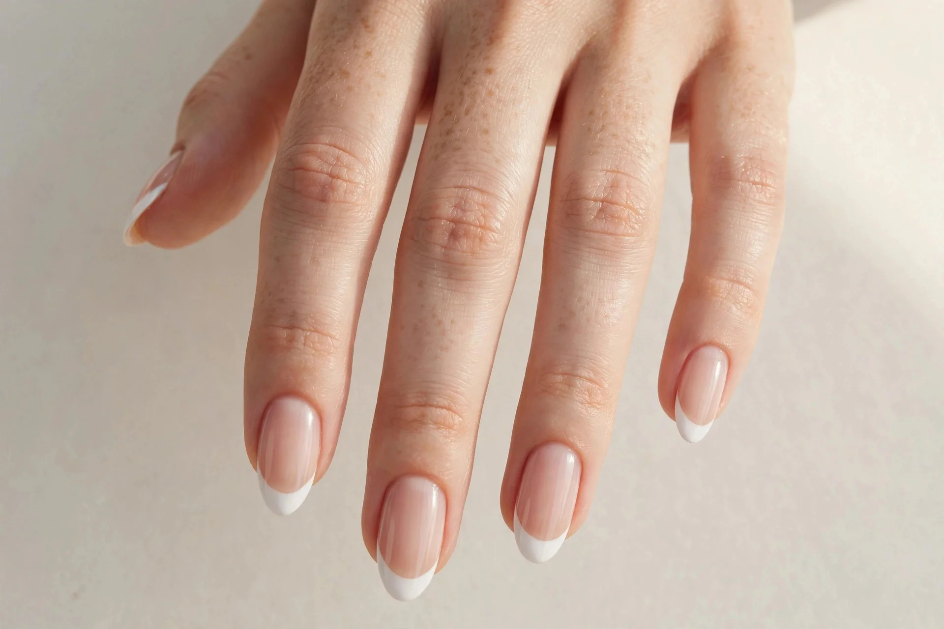 Close-up of classic white French tip manicure with crisp white smile lines on a sheer nude base