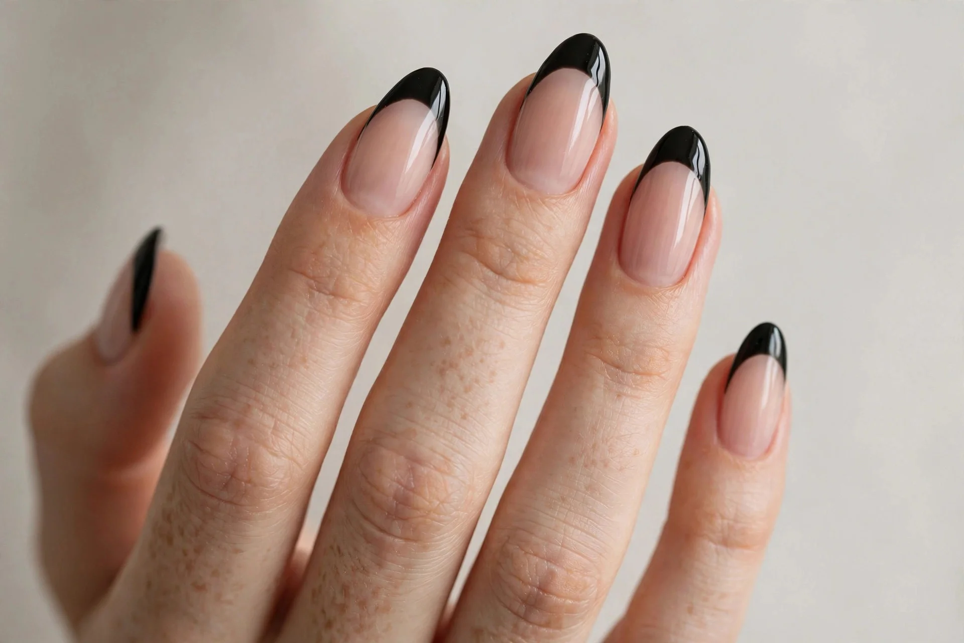 Close-up of bold black French tip manicure with glossy black tips on nude nails