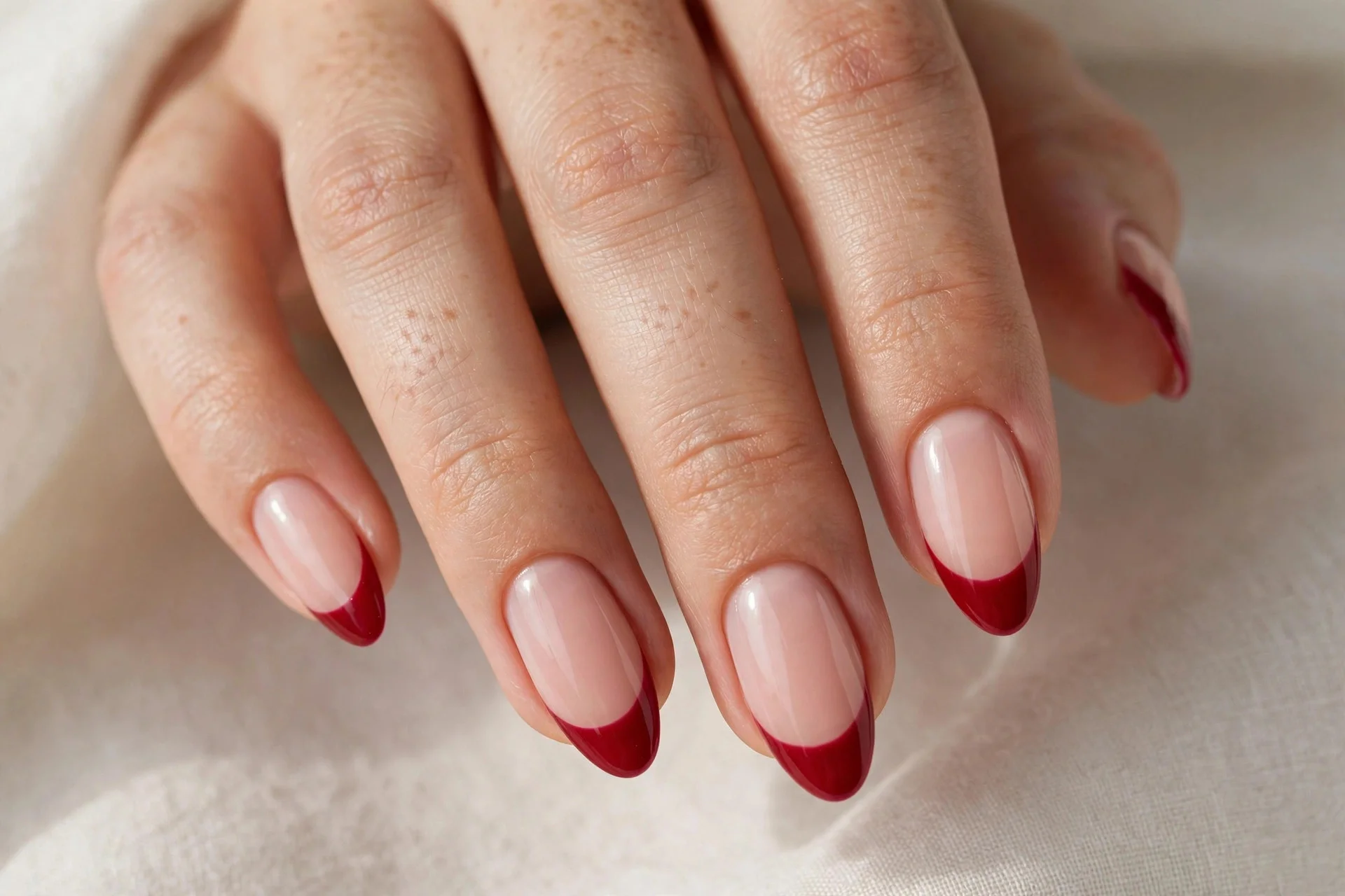 Close-up of red French tip manicure with crimson tips on a nude base