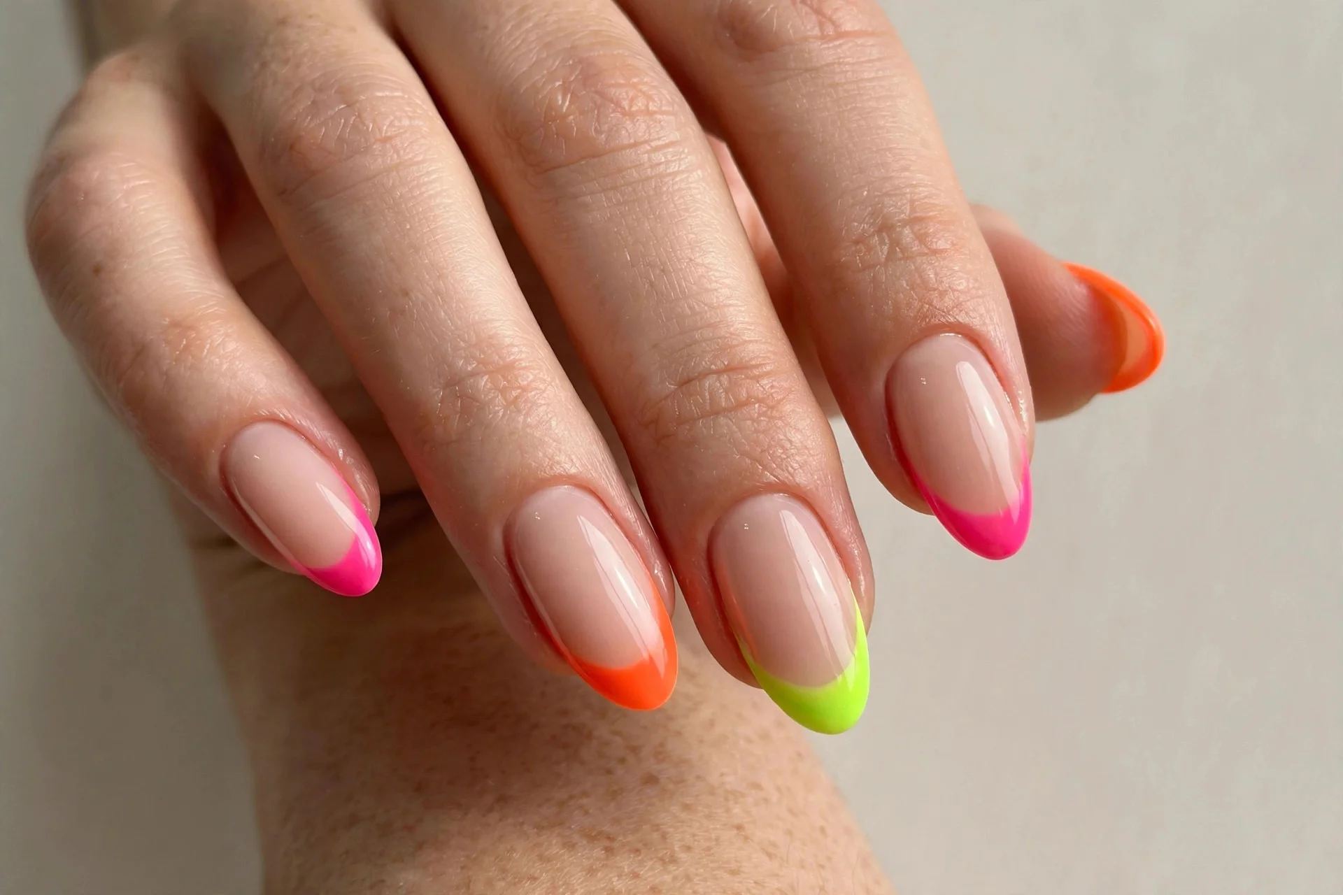 Close-up of neon French tip manicure with bright neon pink, orange and lime tips