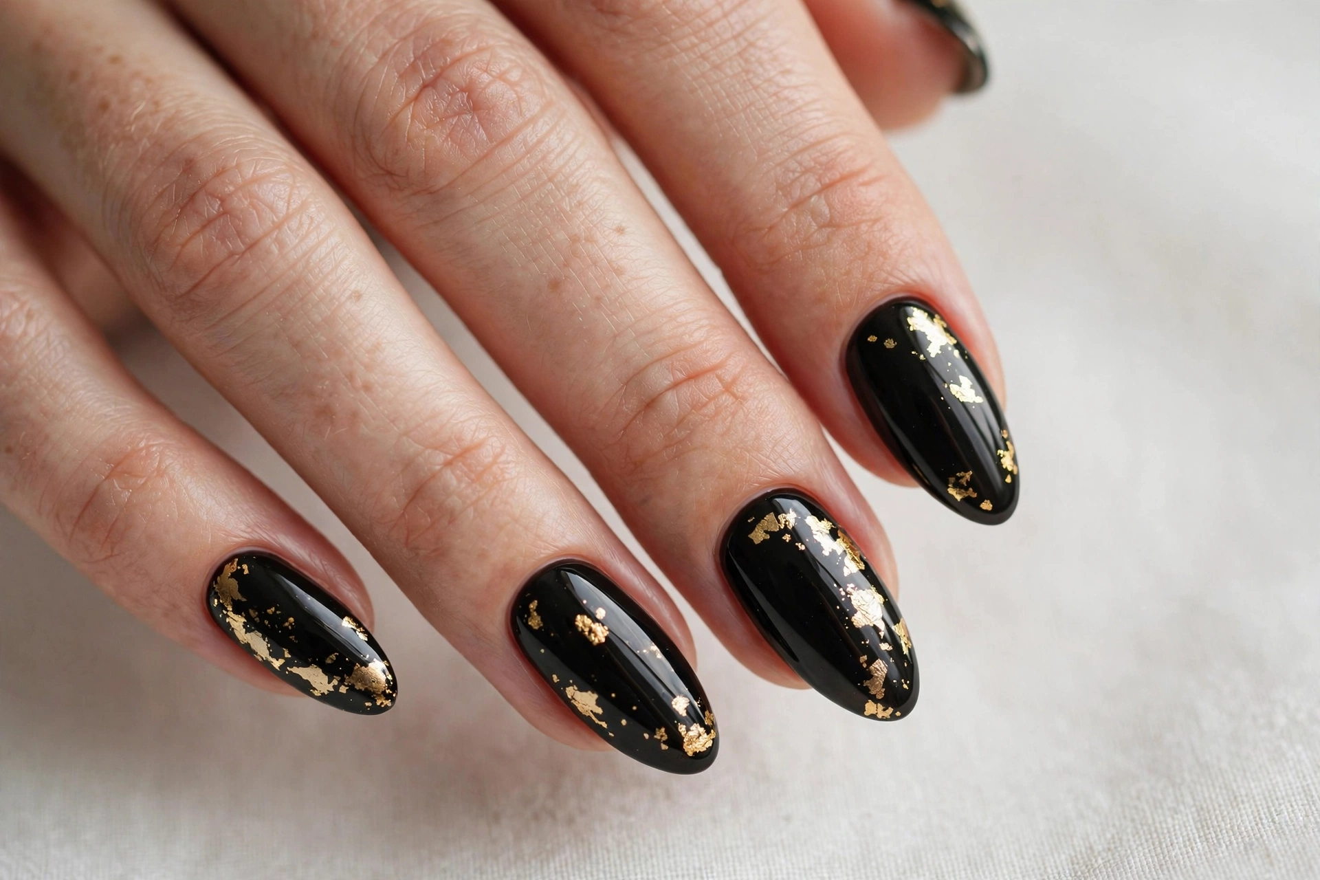 Black gel nail design with gold foil flakes