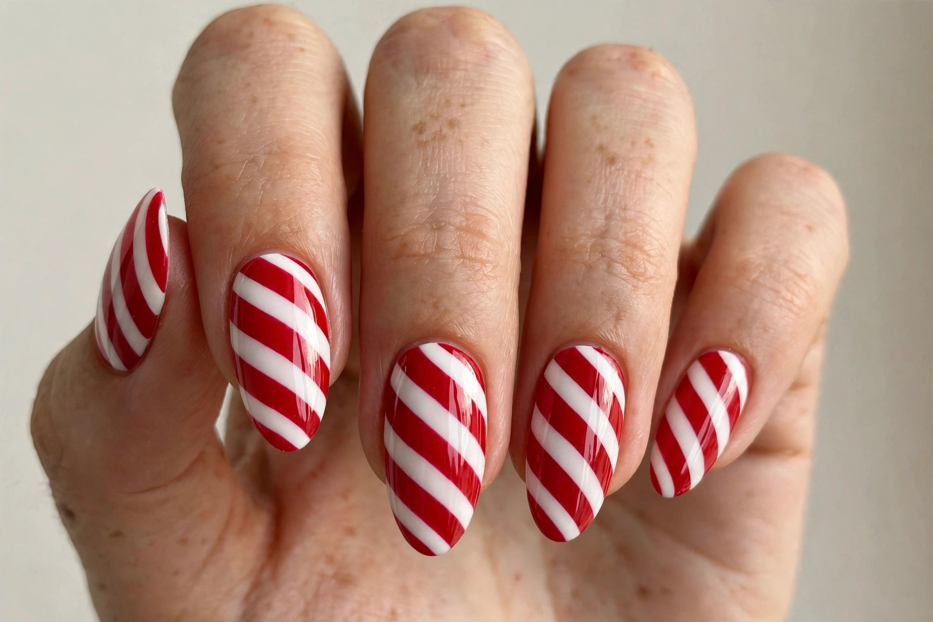 Red and white diagonal candy cane striped gel nails