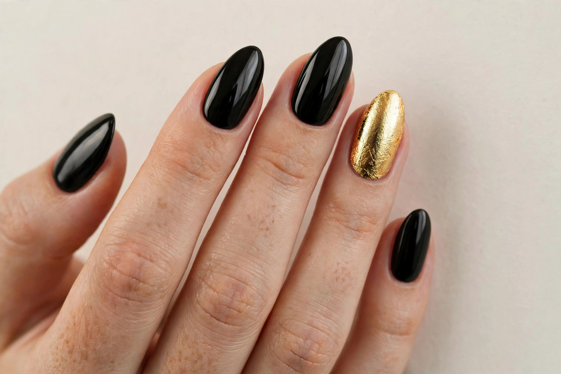Single gold foil accent nail among black manicured nails