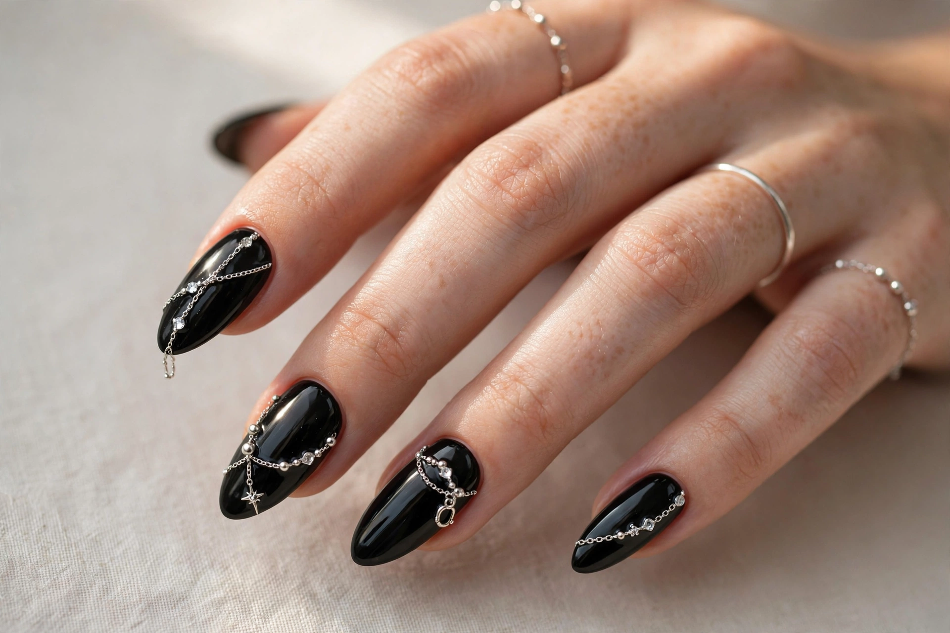 Black nails decorated with delicate silver chain and jewelry details