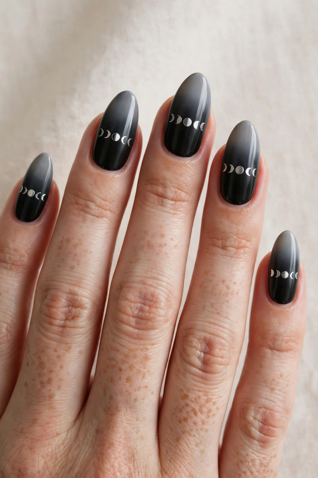 Silver moon phase symbols in a row on black gradient nails