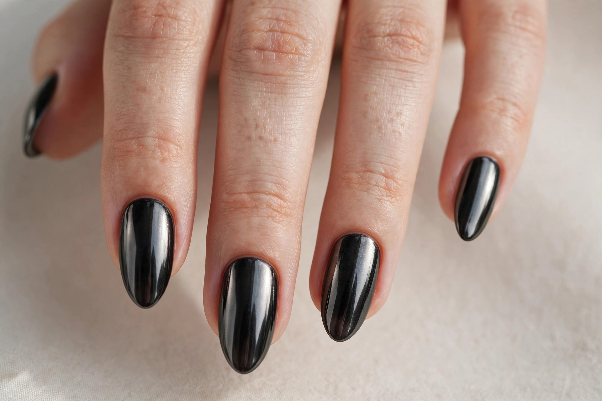Black chrome manicure with mirror-like metallic shine on almond nails